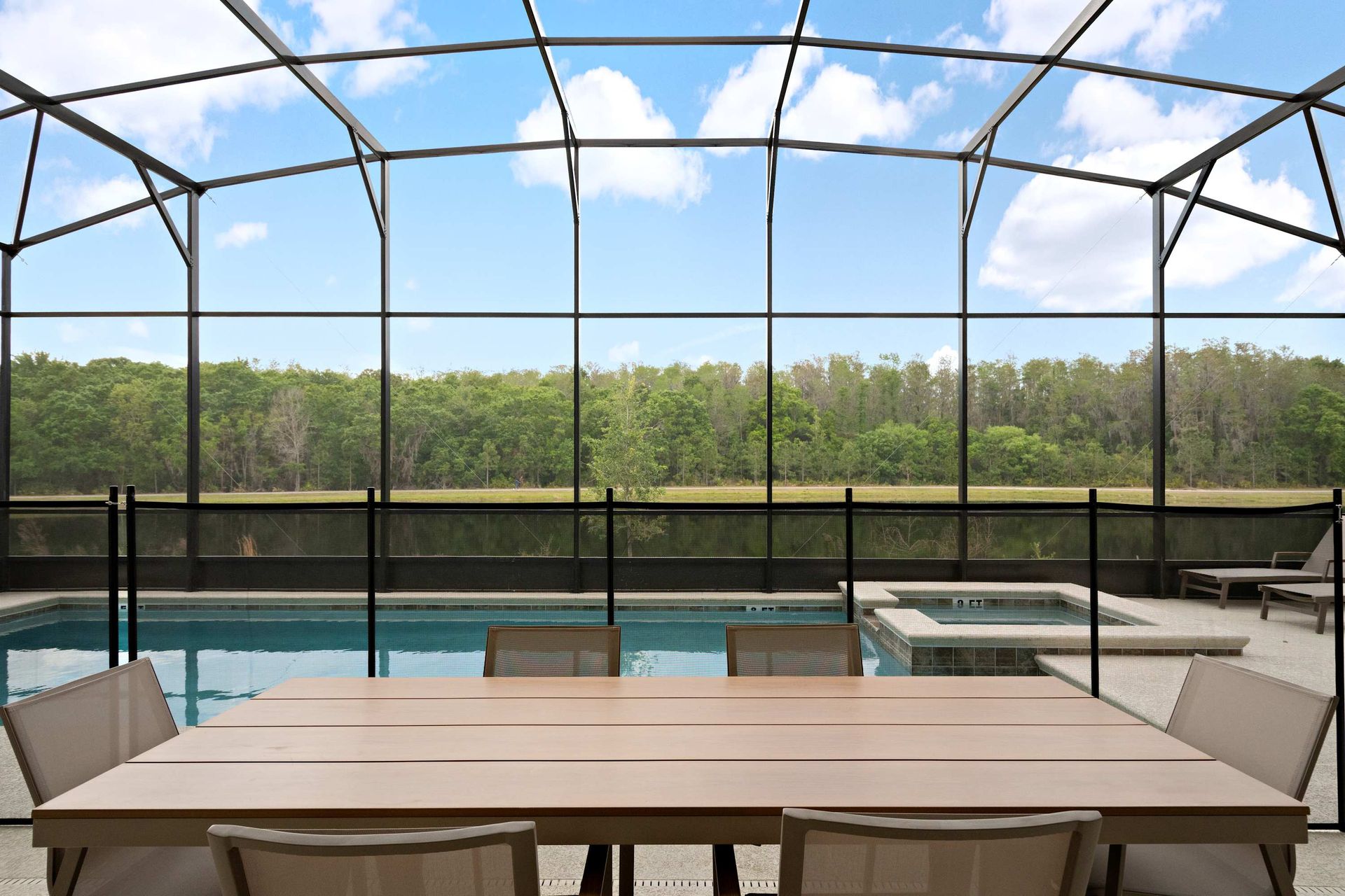 Spacious screened-in pool area with safety fence, loungers, and covered patio dining
