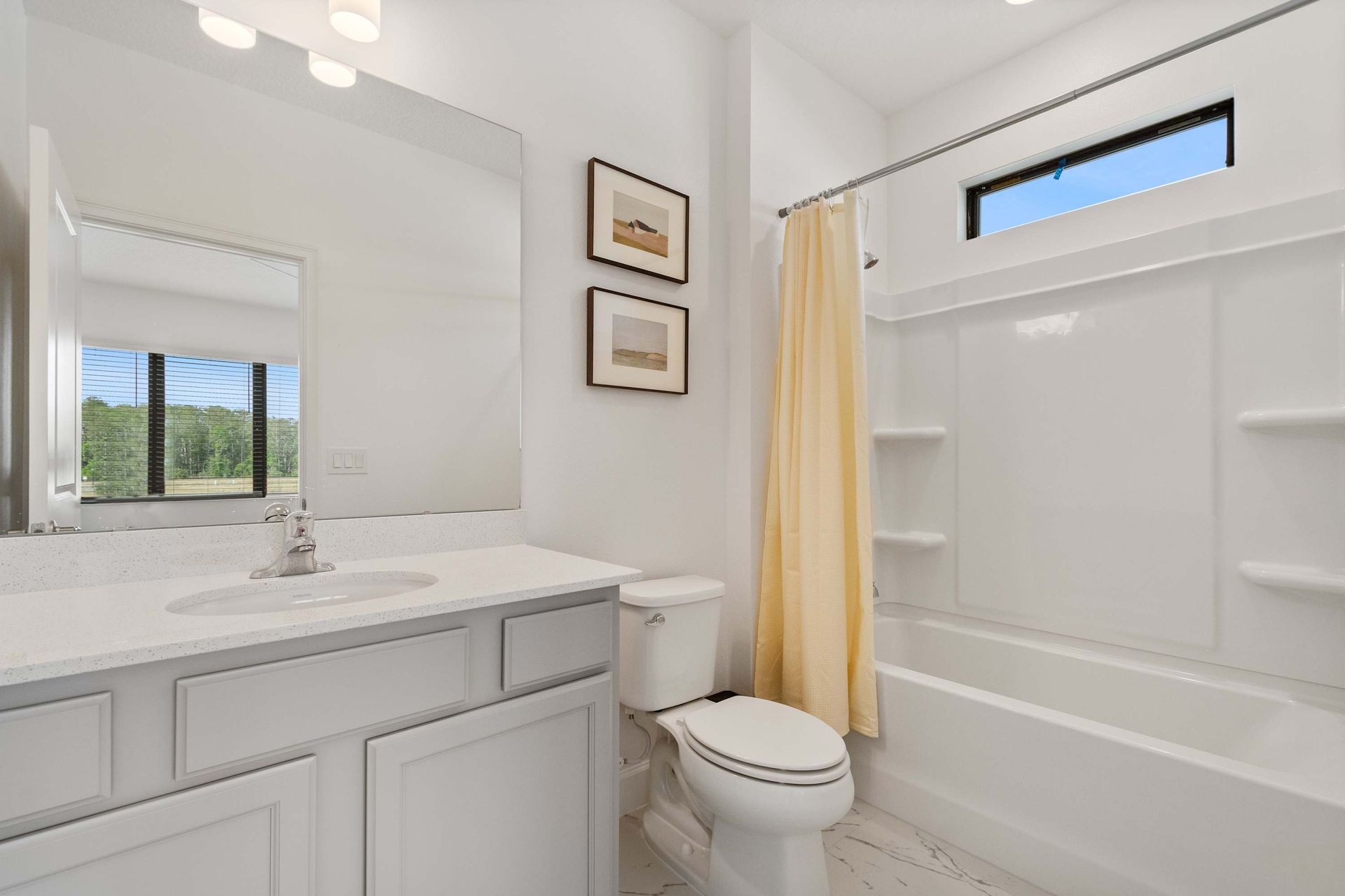 Soft and serene bathroom with light yellow accents, modern vanity, and full tub combo
