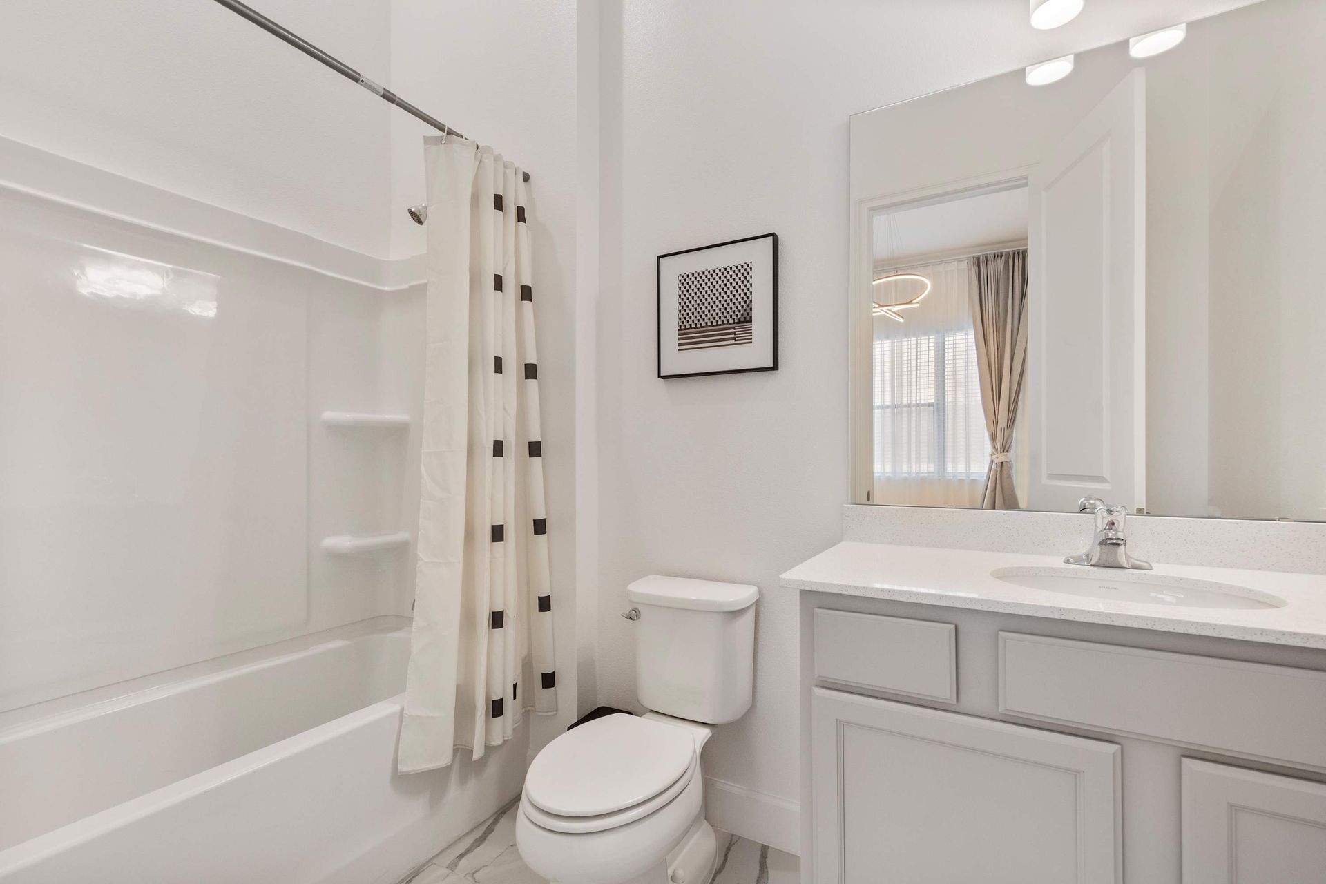 Bright and stylish bathroom with tub/shower combo, modern vanity, and elegant accents
