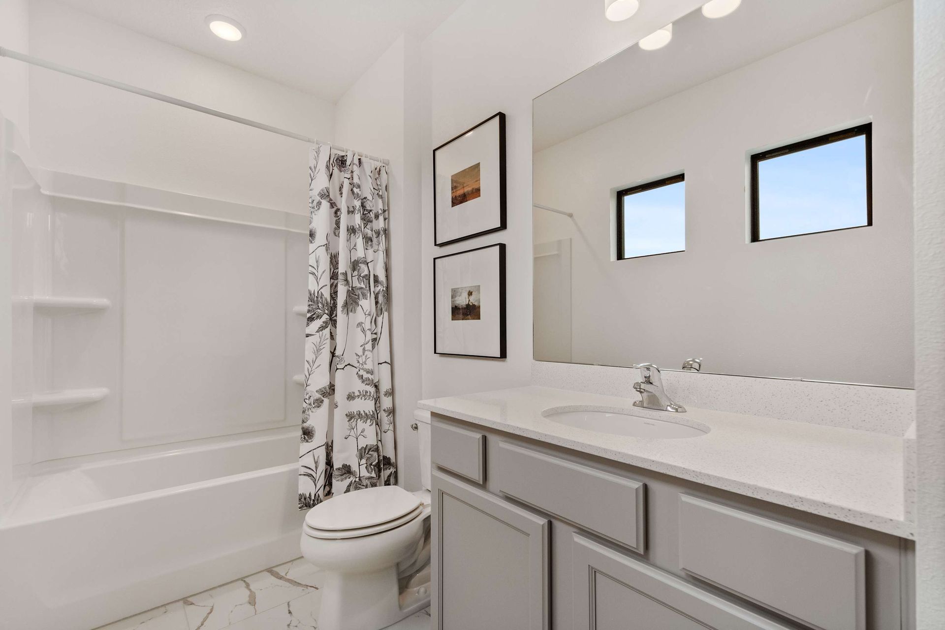 Modern and airy bathroom with patterned shower curtain, sleek vanity, and natural light
