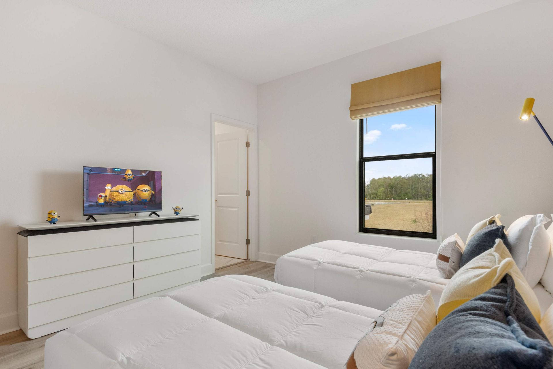 Bright and cheerful twin bedroom with TV, playful decor, and serene outdoor views
