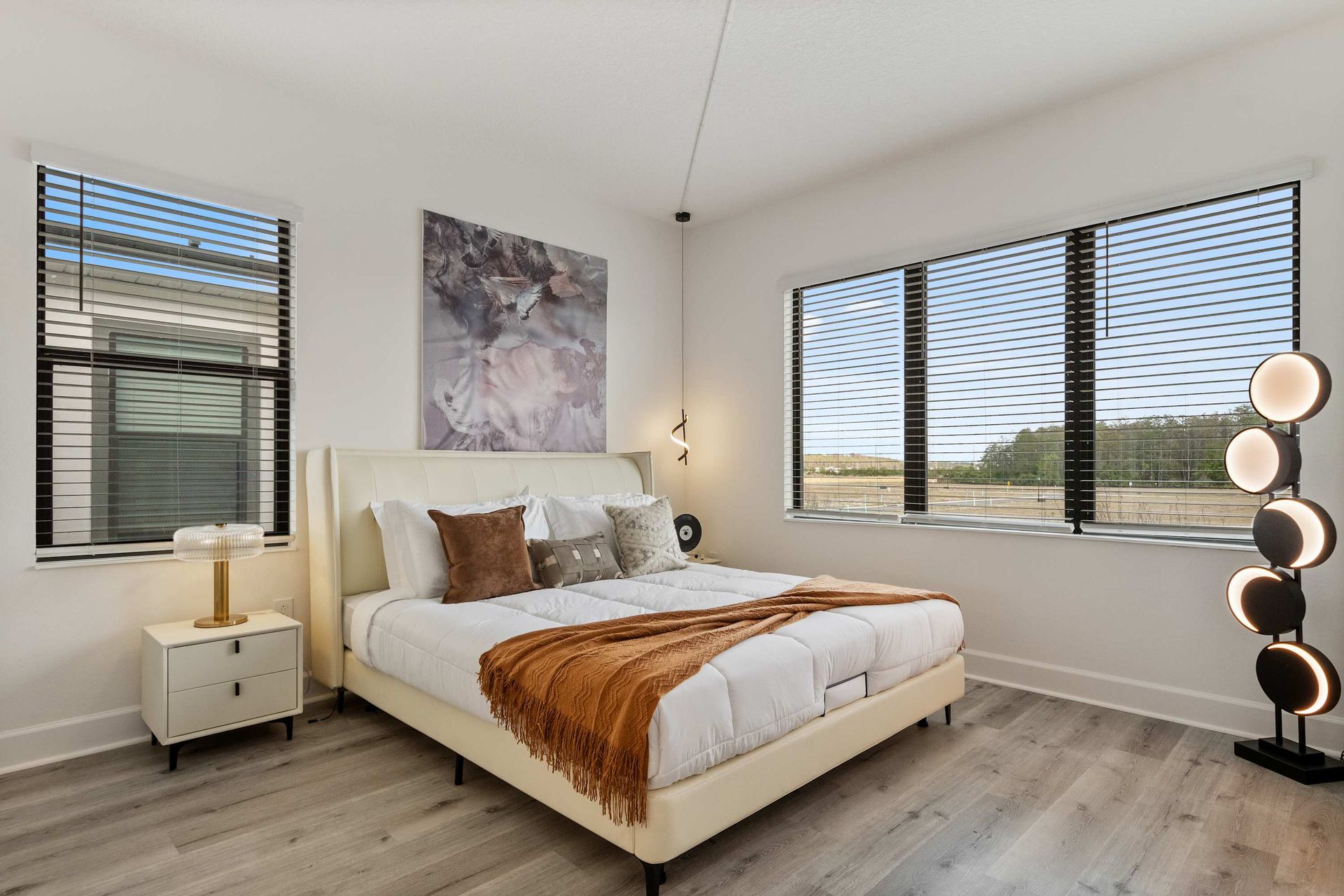 Bright corner bedroom with modern style, cozy king bed, and serene outdoor views
