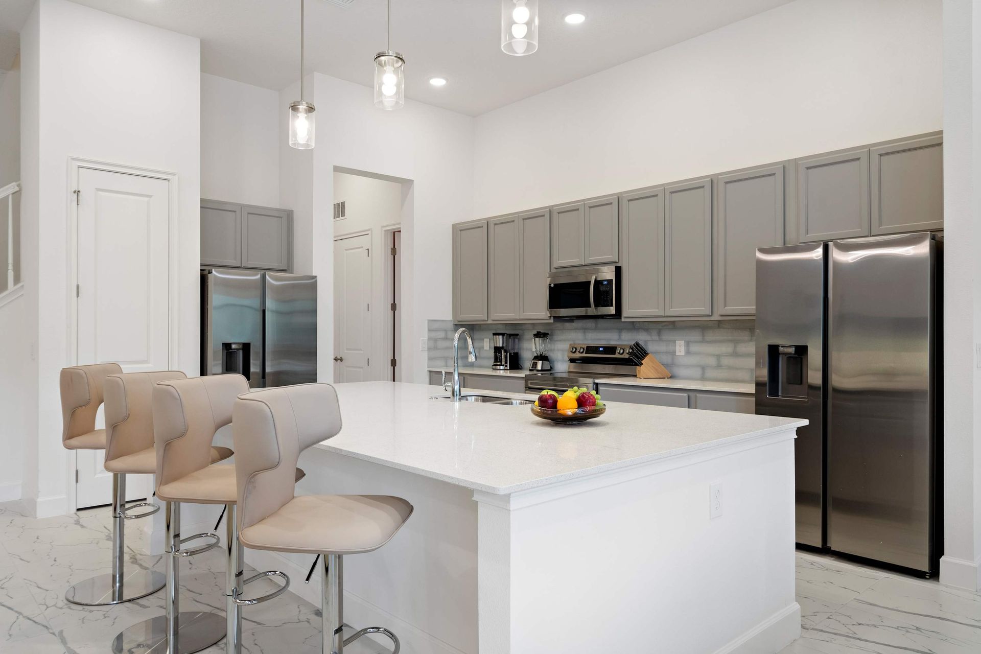 Modern chef’s kitchen with sleek appliances, breakfast bar, and open dining area
