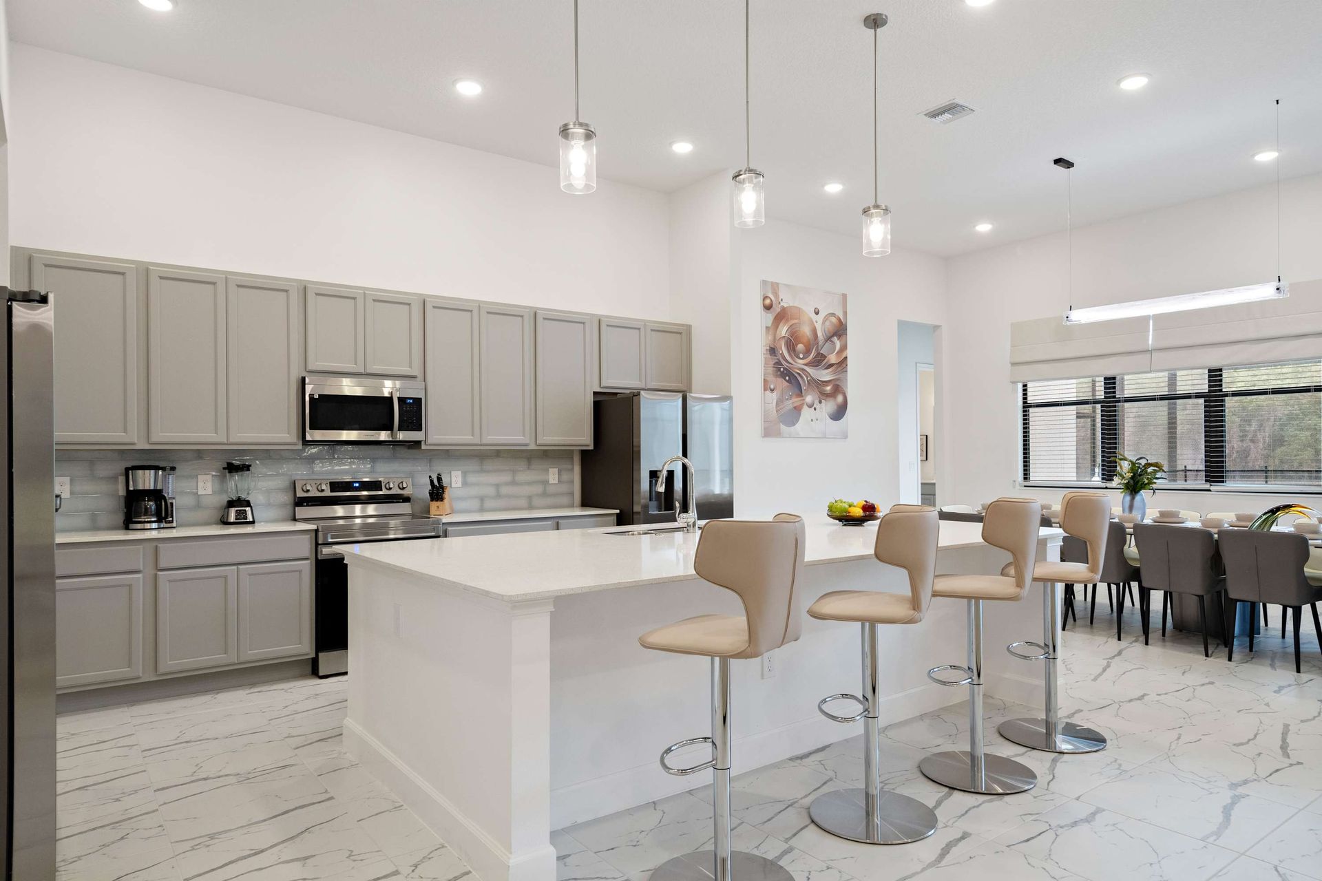 Modern chef’s kitchen with sleek appliances, breakfast bar, and open dining area
