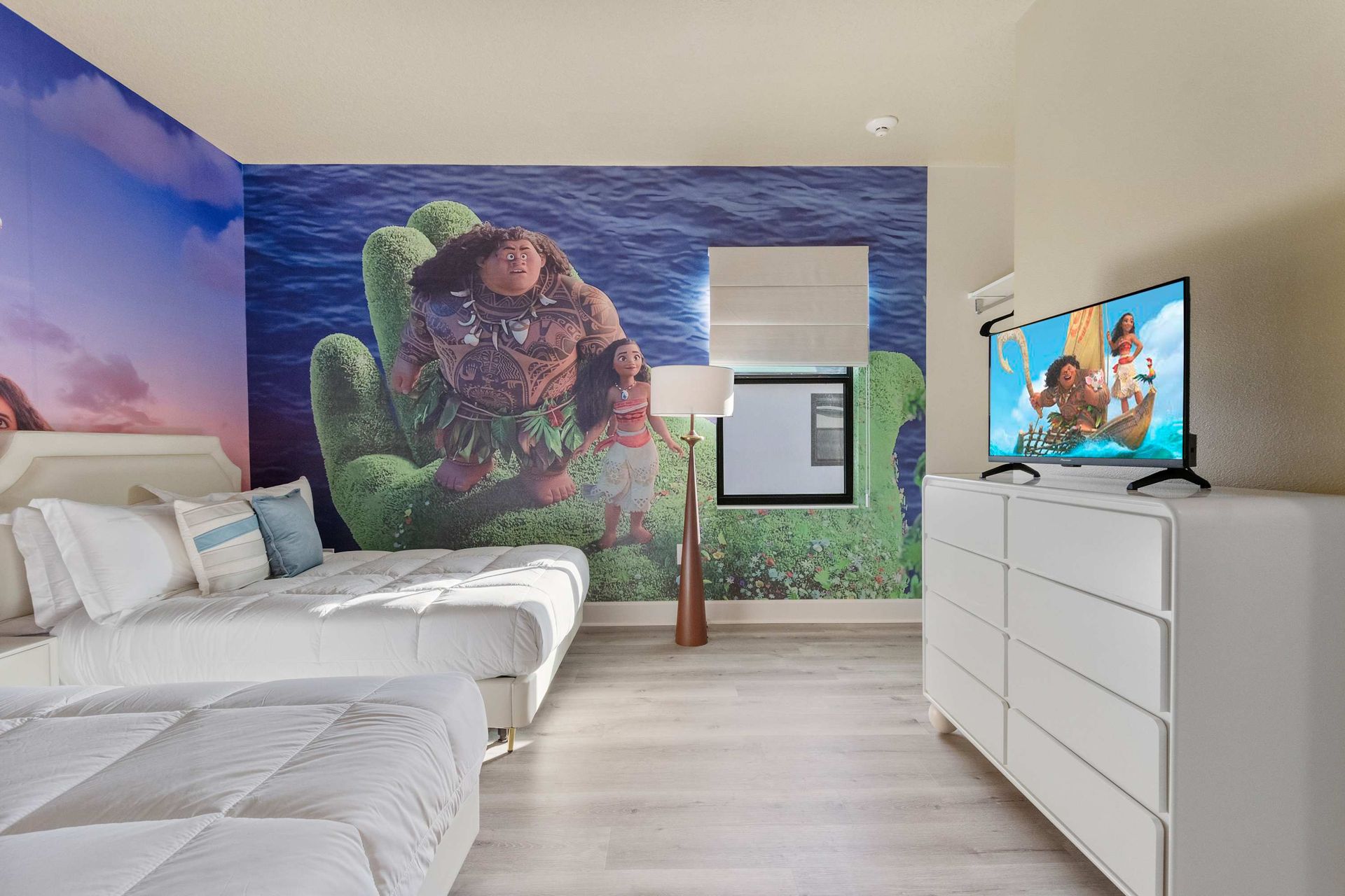 Tropical ocean-themed kids’ room with twin beds and bold adventure wall mural

