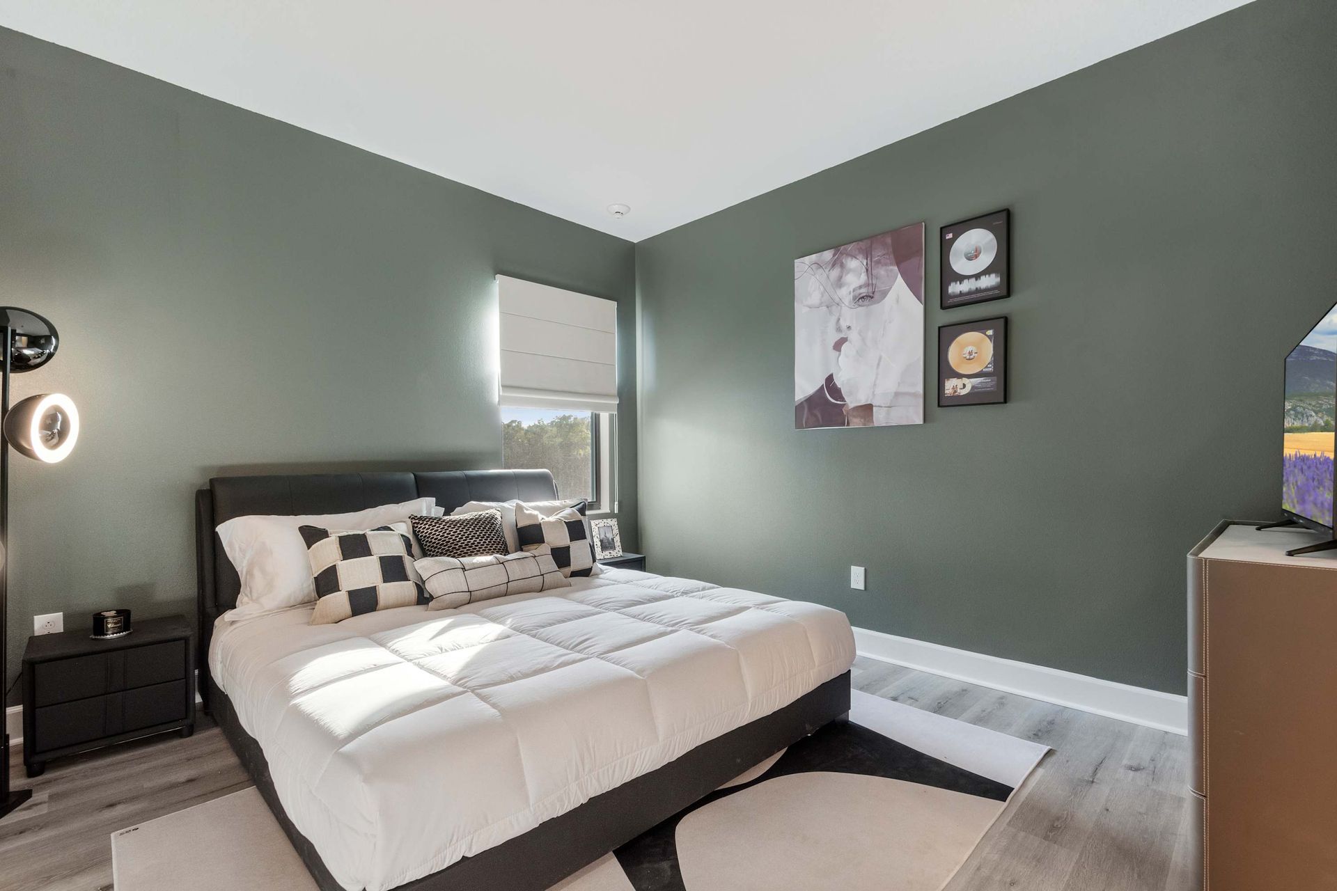 Sleek bedroom with racing-inspired décor, cozy bed, and deep green accent walls
