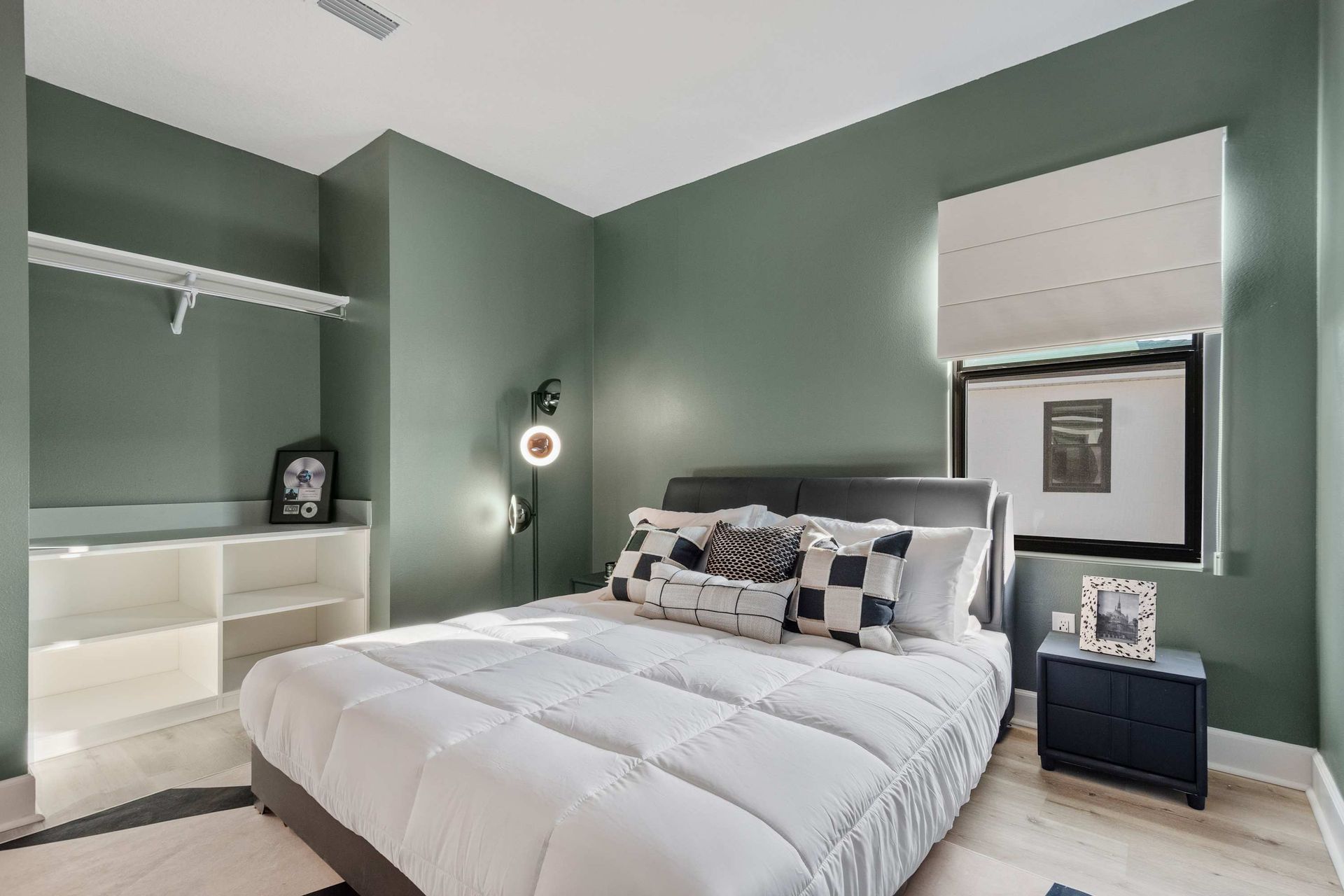 Sleek bedroom with racing-inspired décor, cozy bed, and deep green accent walls
