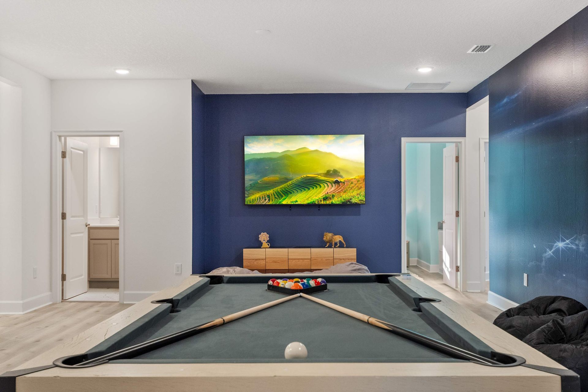 Game room with pool table, large smart TV, and bold accent wall for fun nights in
