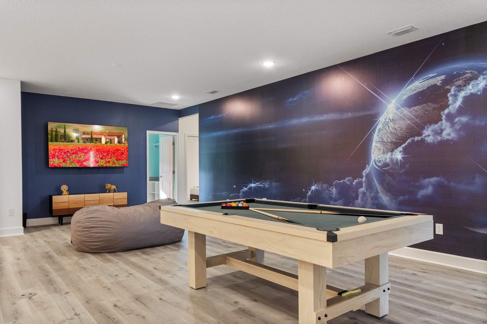 Game room with pool table, large smart TV, and bold accent wall for fun nights in
