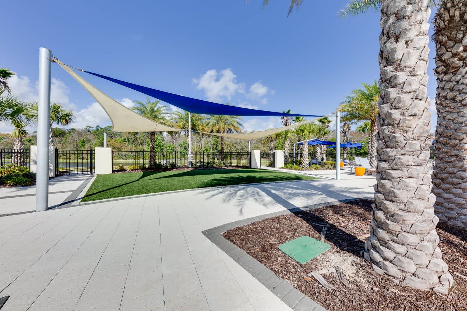 Stylish shaded relaxation area amid palms, lush landscaping, peaceful retreat.
