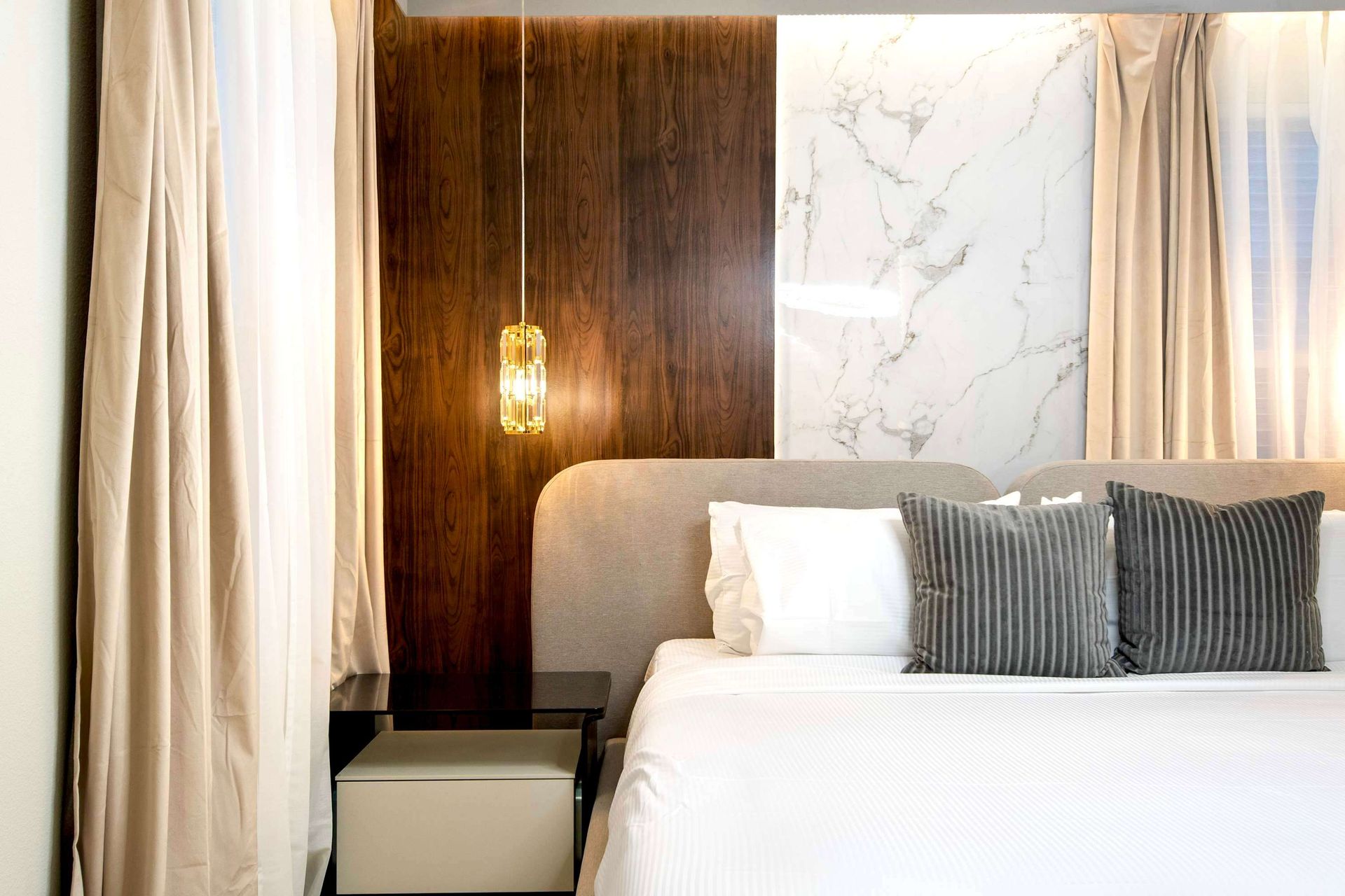 Modern minimalist bedroom with elegant lighting, marble accents, and neutral tones
