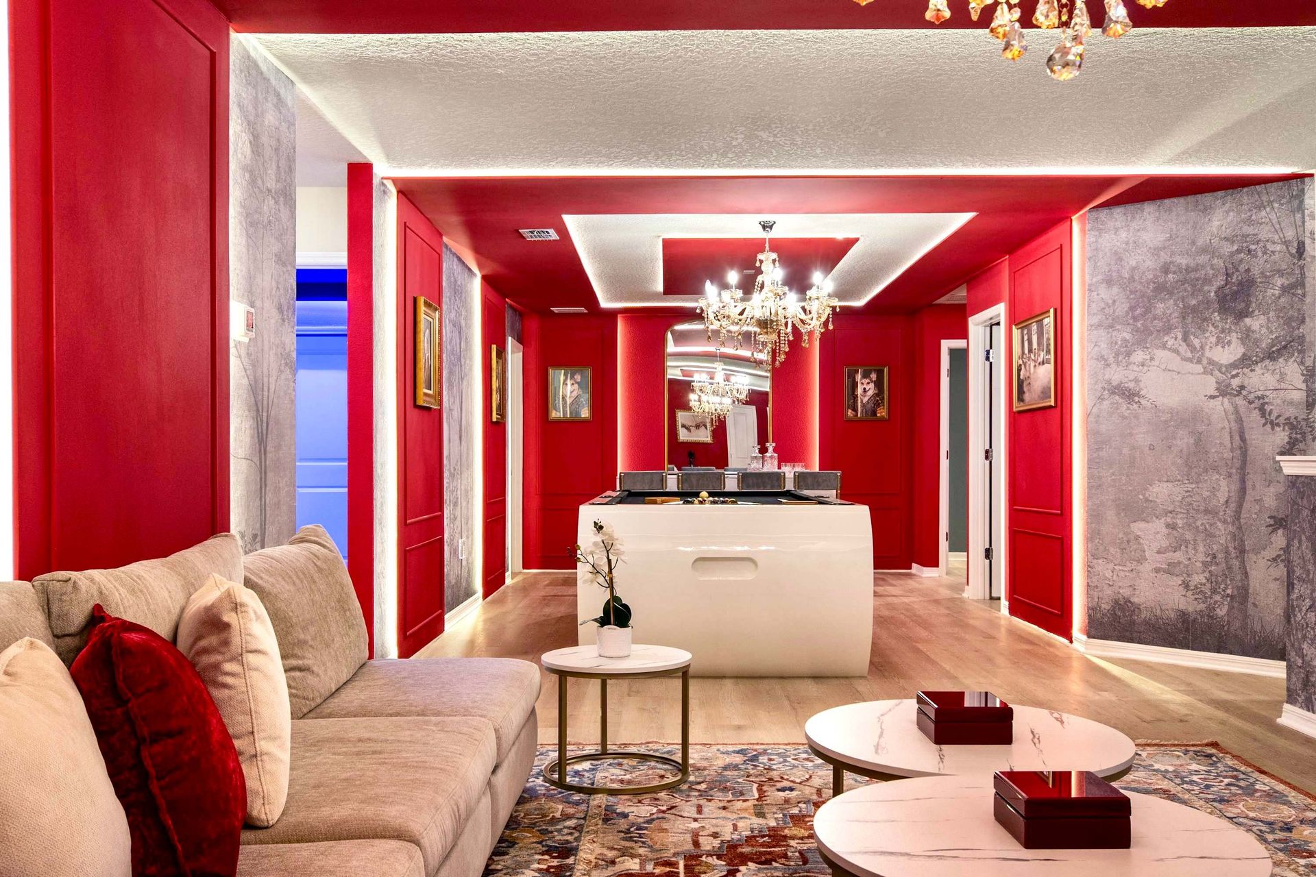 Stylish red-themed lounge with modern game table, plush seating, and chandeliers
