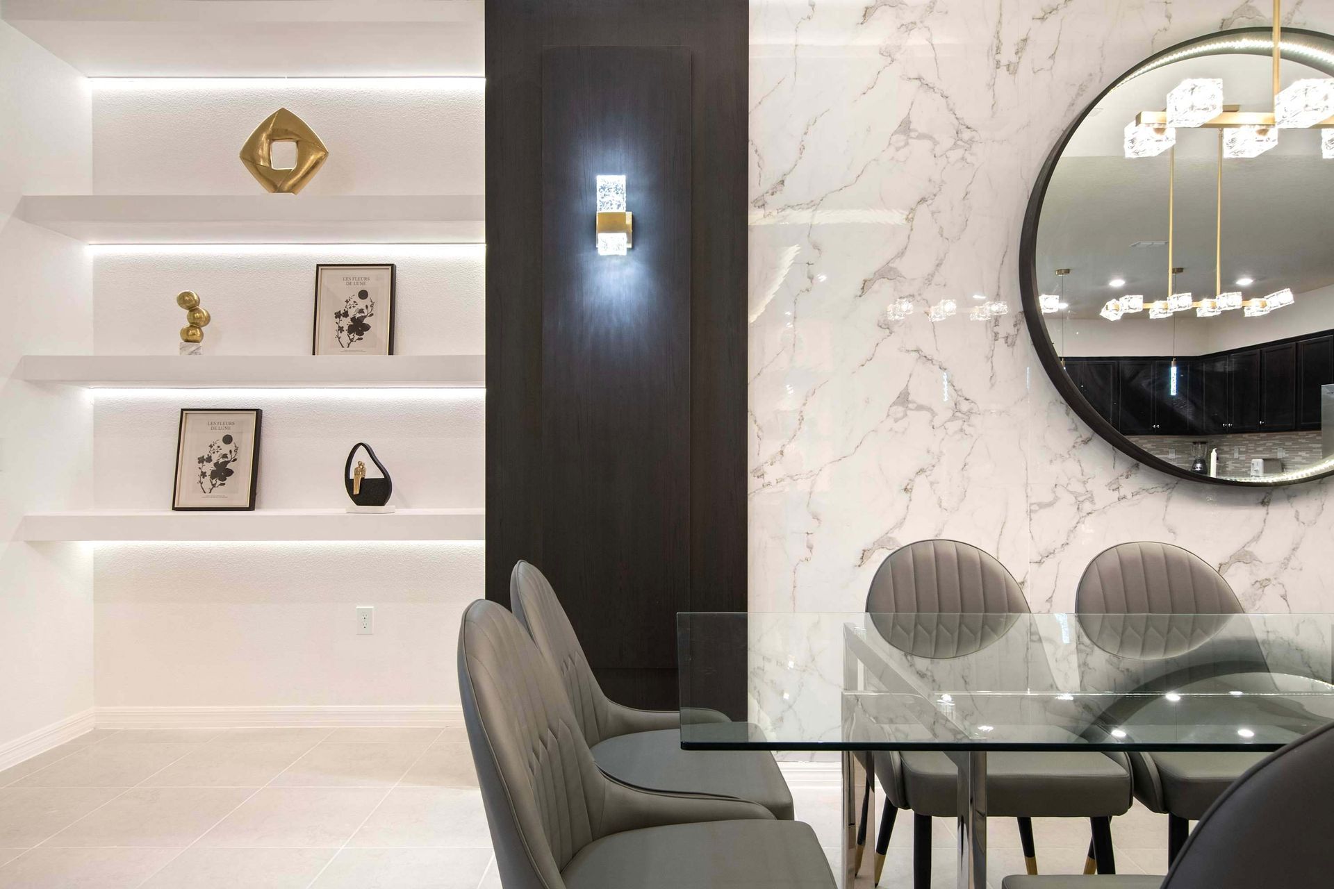 Modern dining space with marble accents, sleek glass table, and artistic wall shelves
