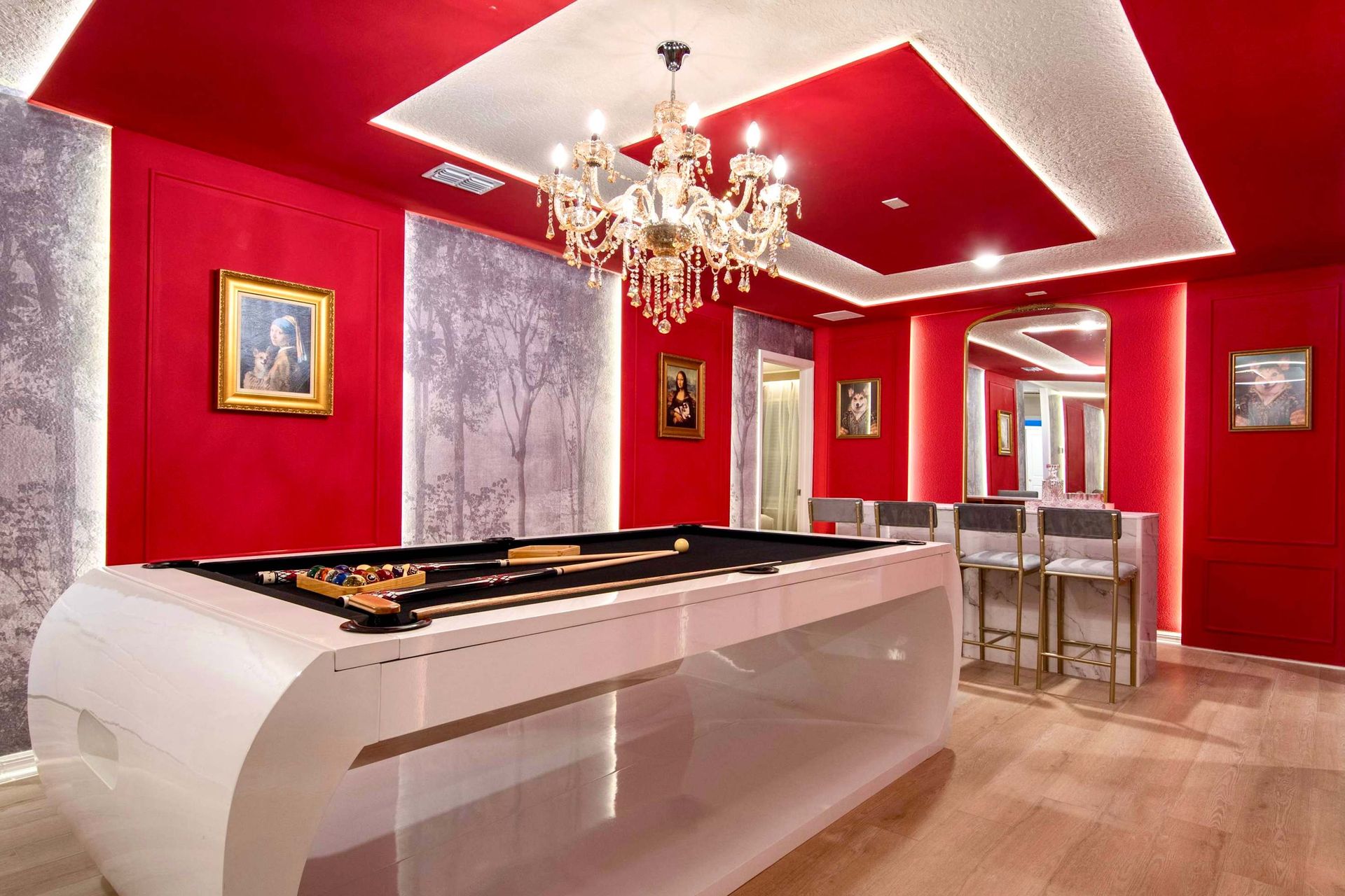 Luxurious game room with bold red walls, modern pool table, and crystal chandelier
