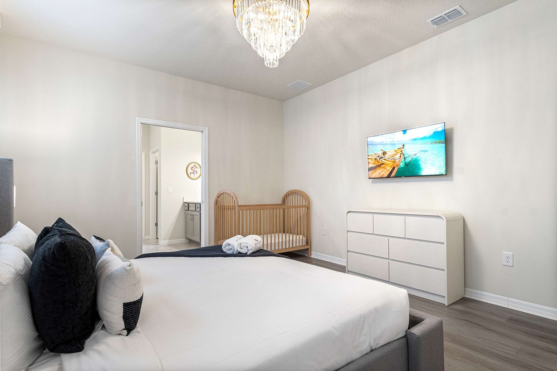 Bright and modern suite with TV, crib, ensuite bath, and calming neutral tones.