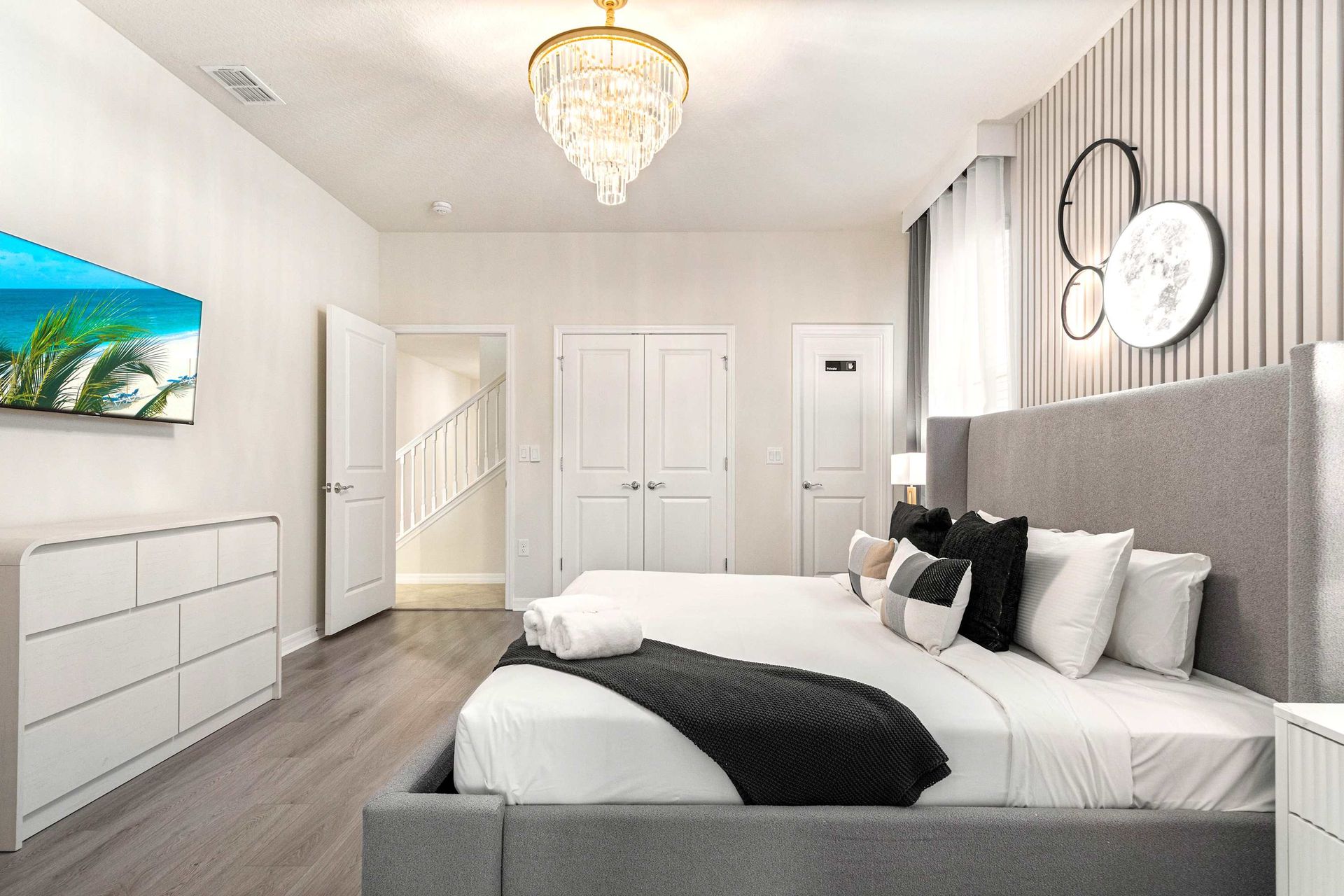 Chic bedroom with luxe chandelier, king bed, and modern décor for pure comfort.