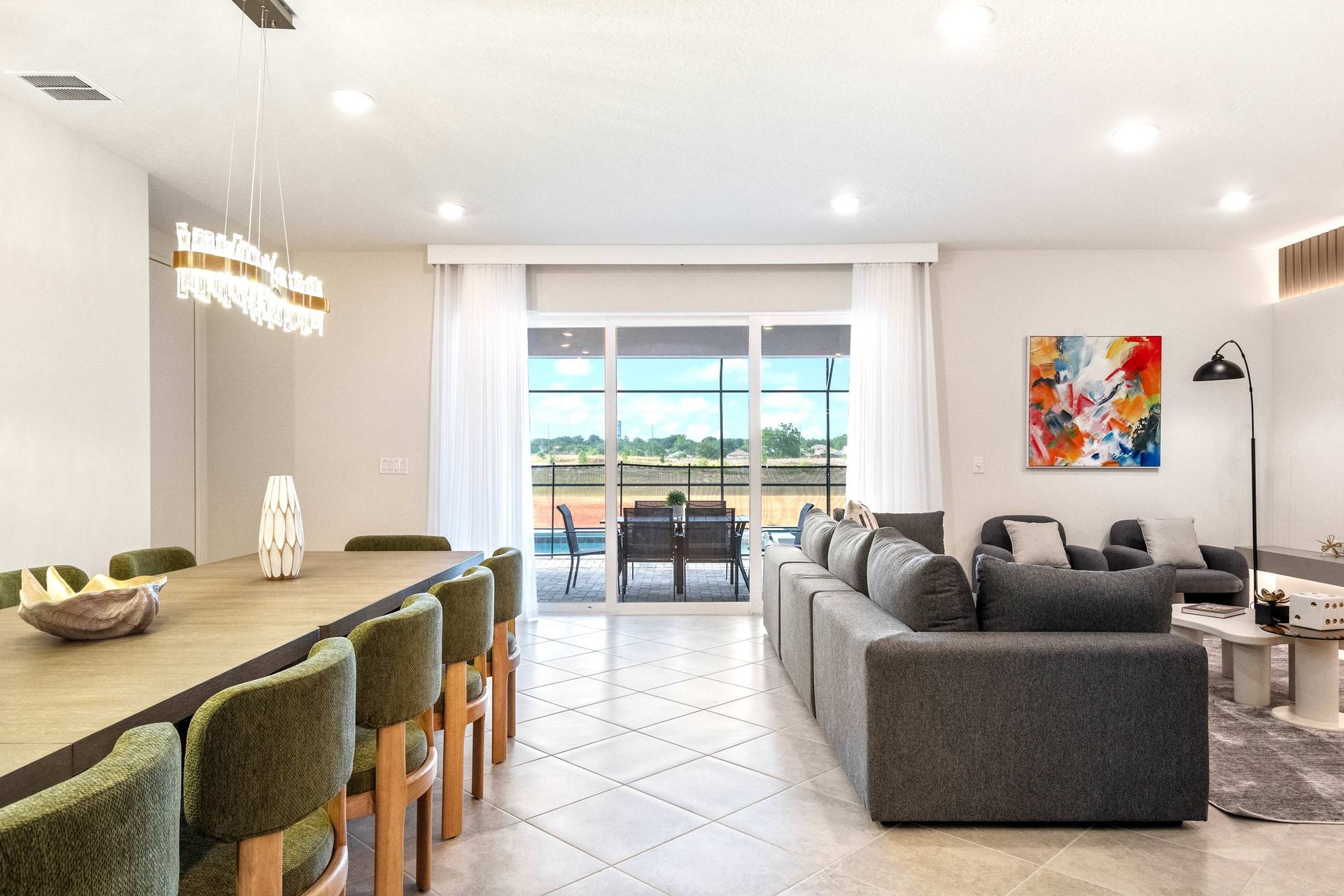 Open-concept living and dining with patio views, plush seating, and chic design