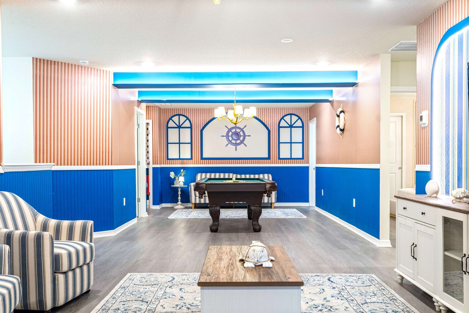 Nautical-style game lounge with pool table, cozy seating, and vibrant decor
