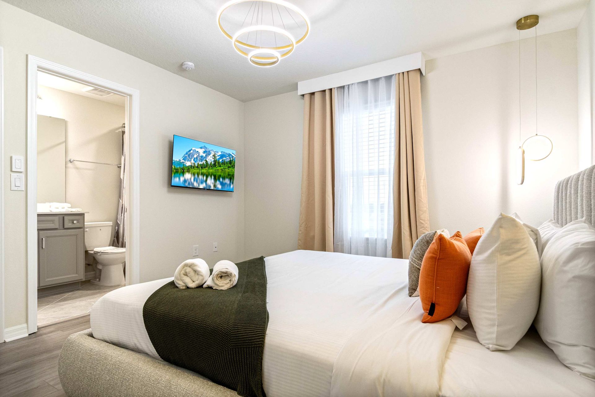 Cozy ensuite bedroom with modern lighting, smart TV, and warm, inviting tones.