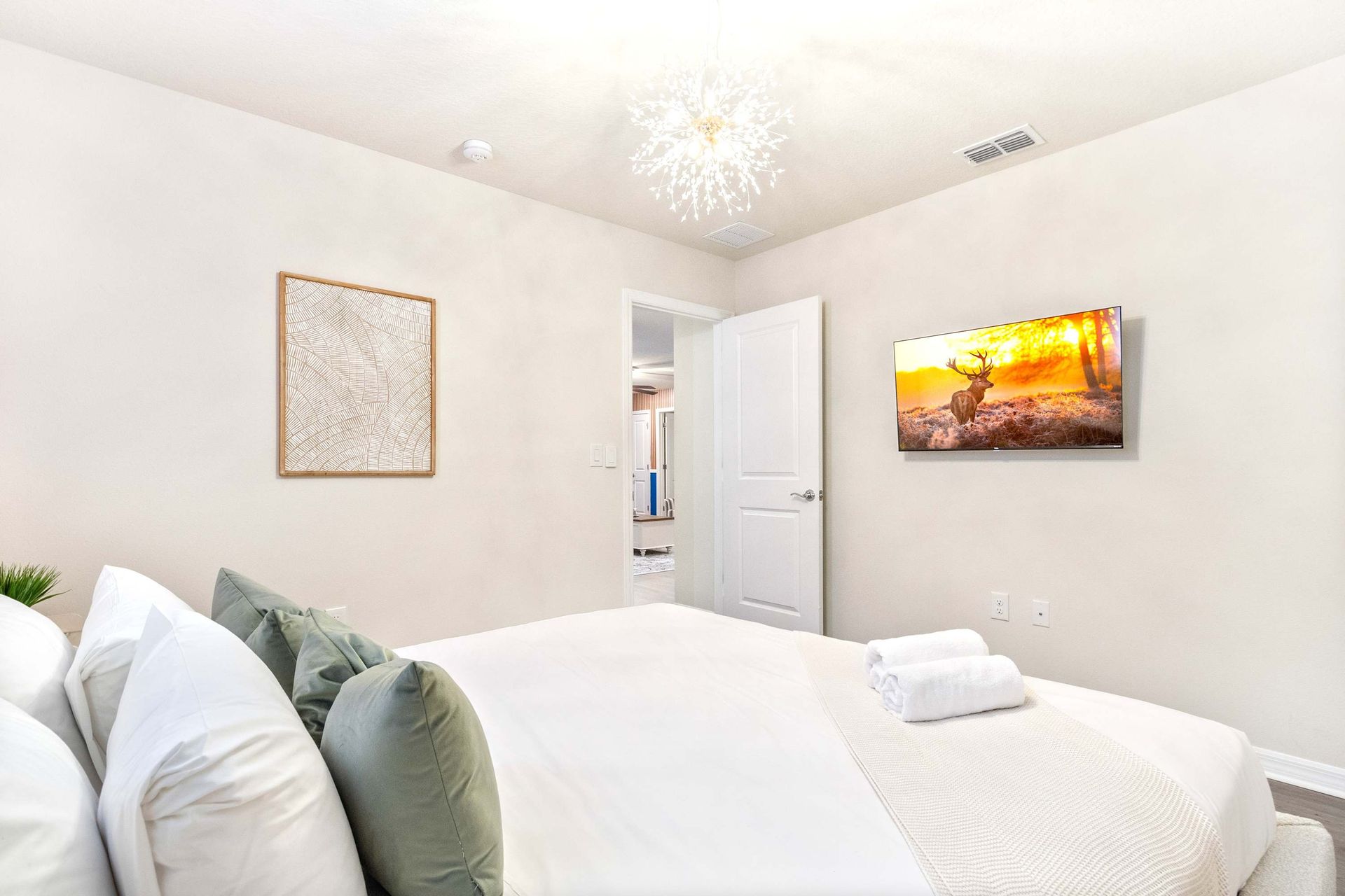 Peaceful retreat with soft tones, cozy bedding, and a mounted smart TV.