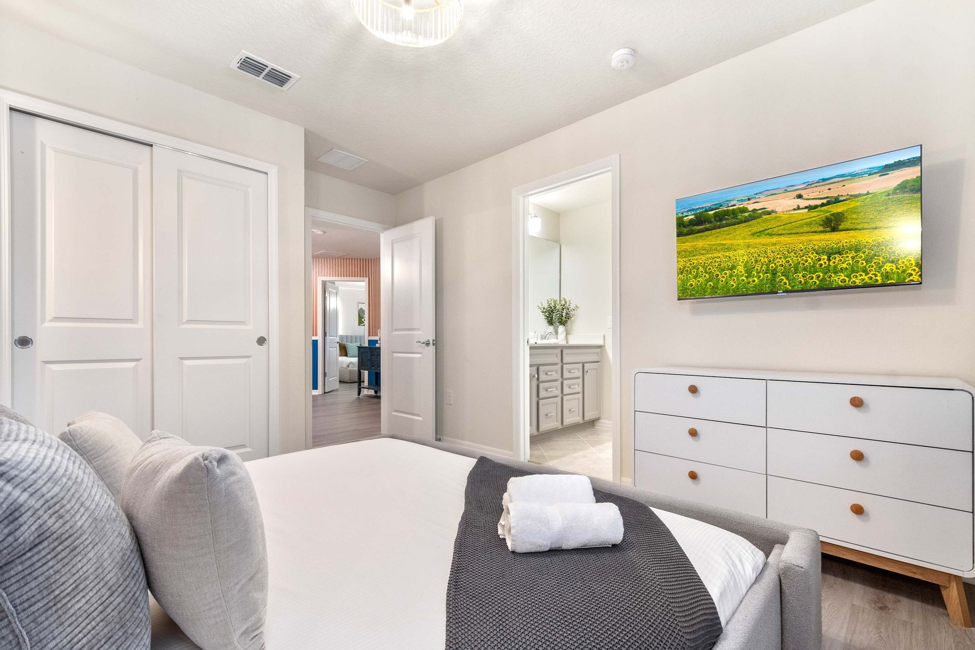 Comfortable ensuite bedroom with smart TV, modern dresser, and soft, neutral tones.