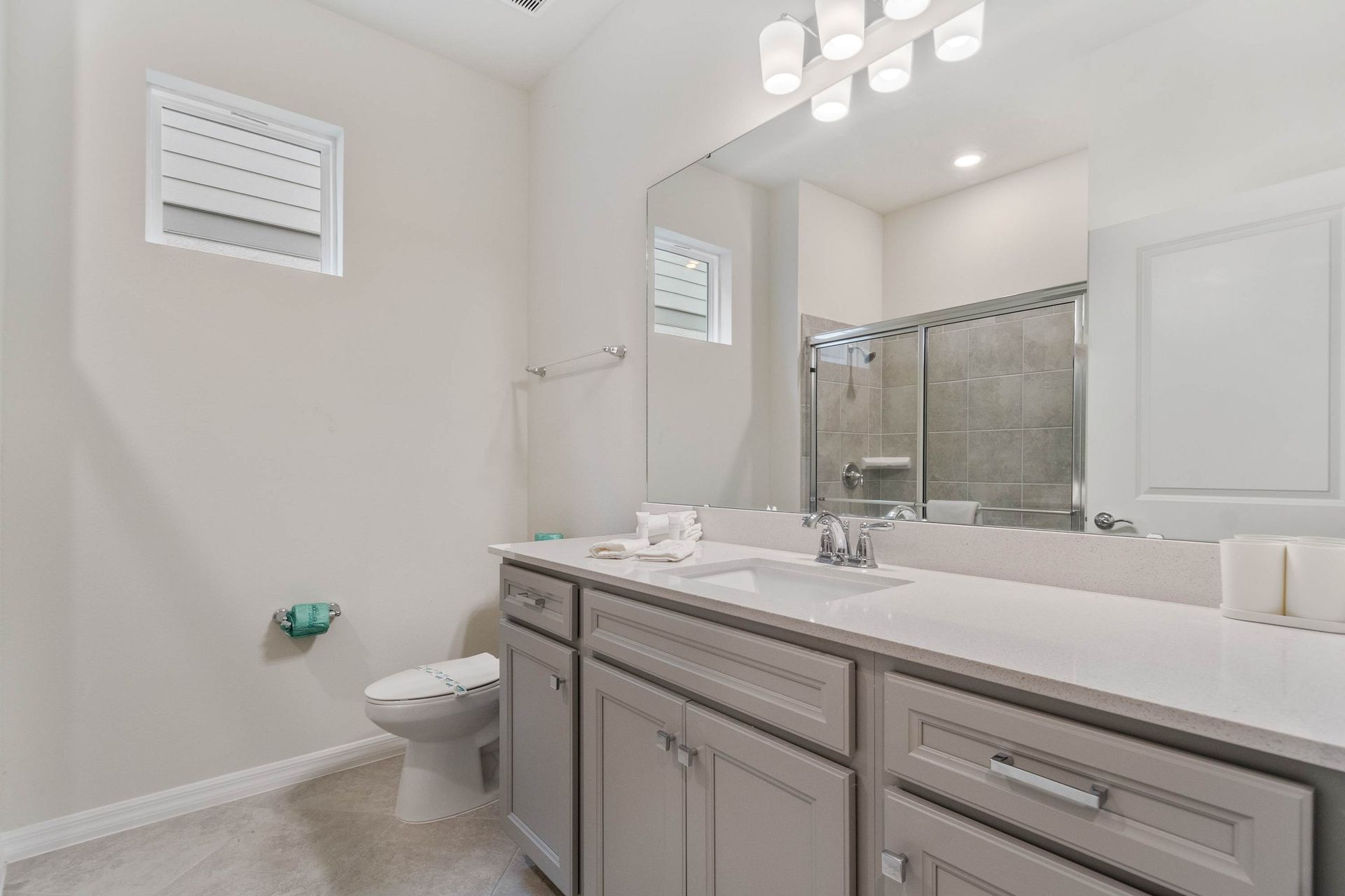 Bright and clean bathroom with large vanity, walk-in shower, and modern finishes.