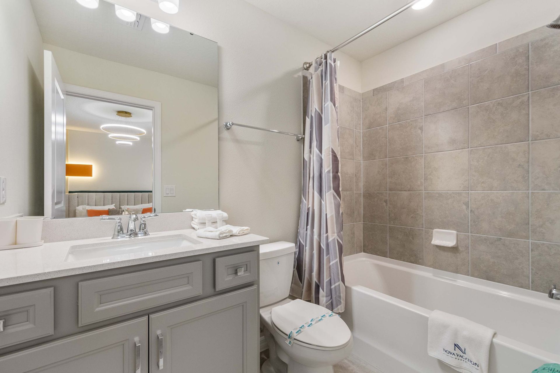 Modern bathroom with a full tub, sleek vanity, and access to a stylish bedroom.