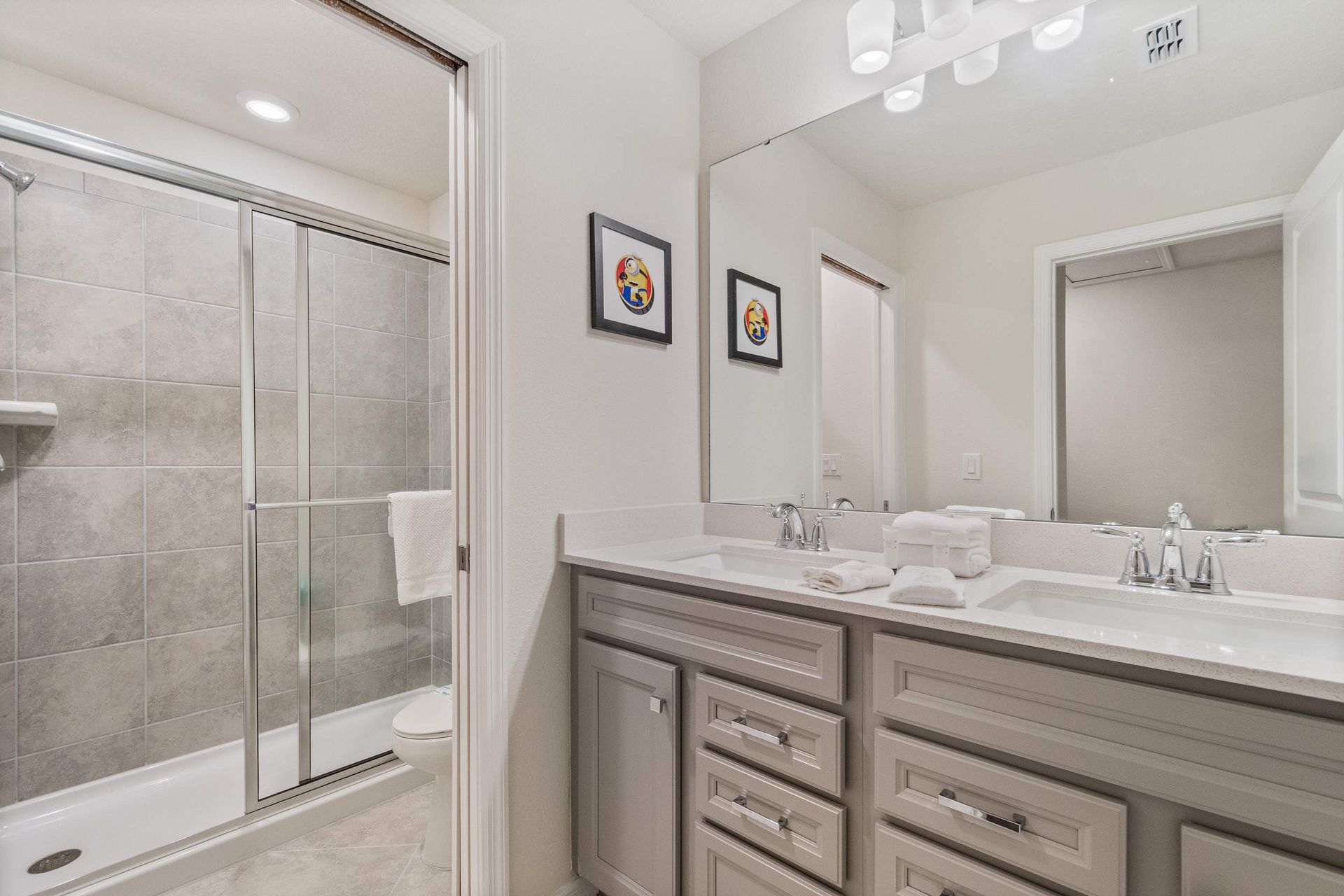 Elegant bathroom with dual sinks, a spacious vanity, and a walk-in glass shower.