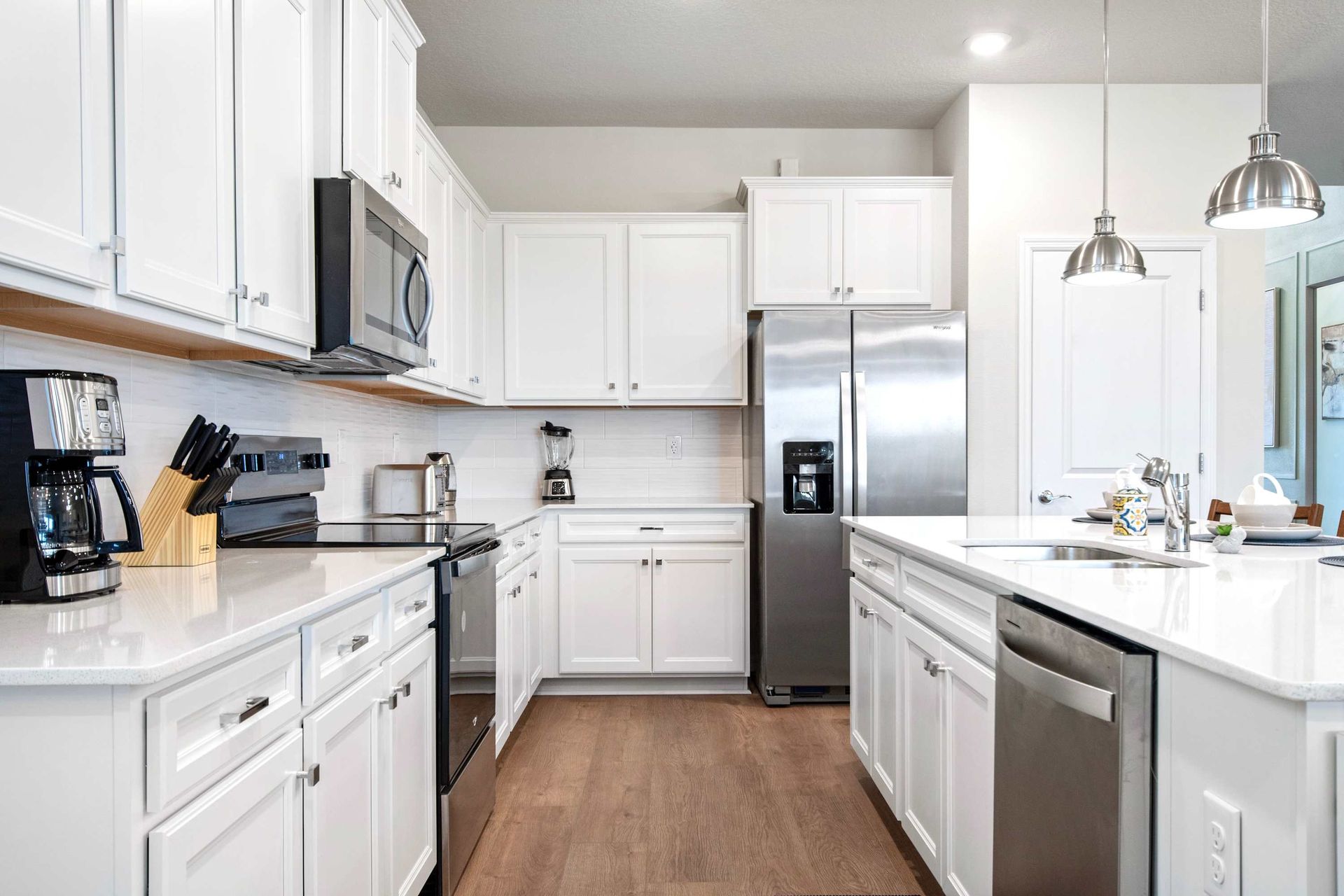 Fully equipped chef’s kitchen with white cabinetry, stainless steel, and ample space.
