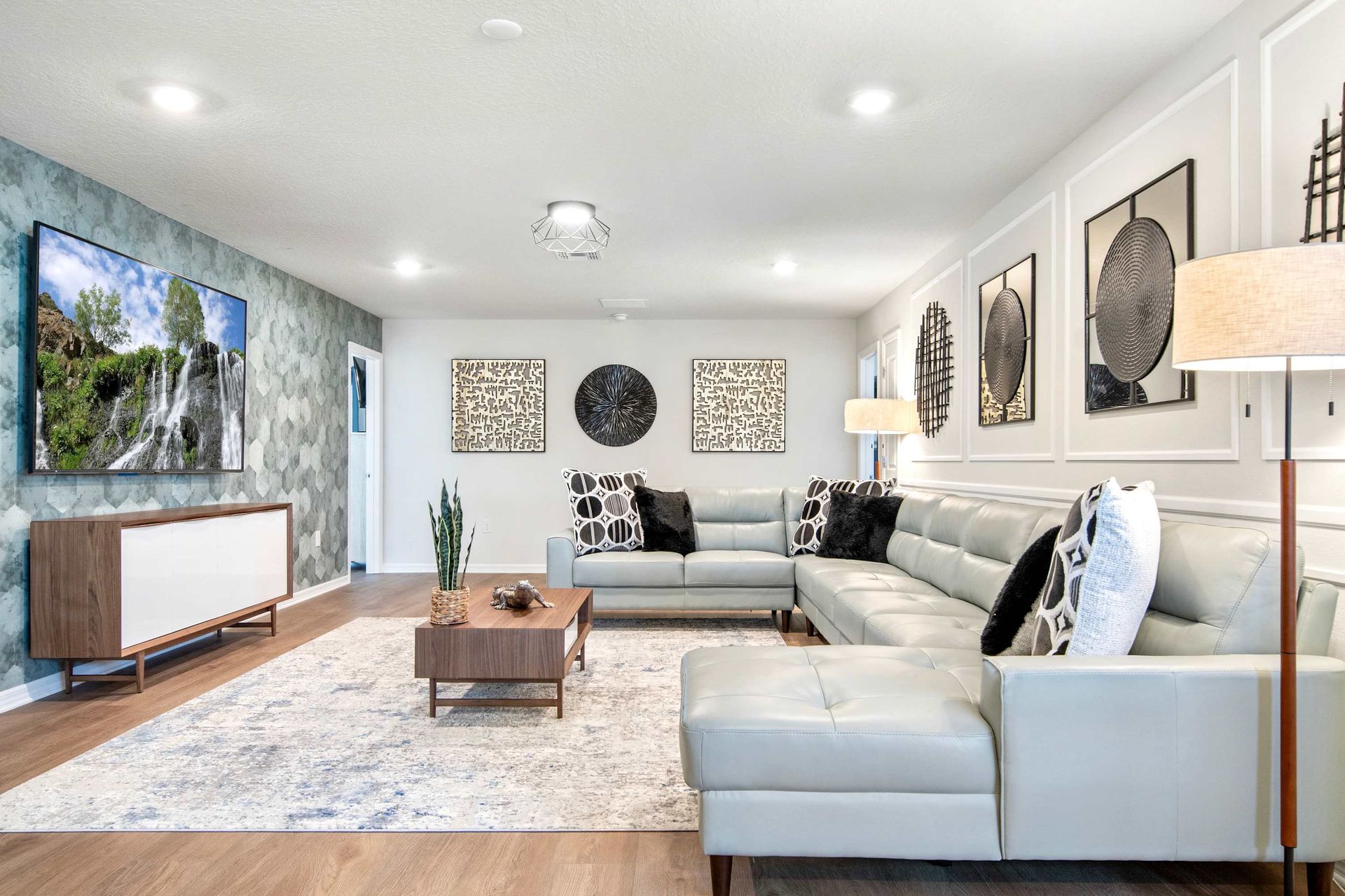 Stylish media room with large sectional, bold décor, and a wall-mounted TV.

