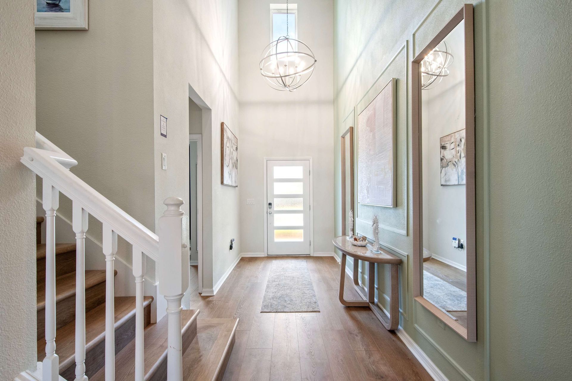 Elegant foyer with high ceilings, modern lighting, and stylish wall accents.
