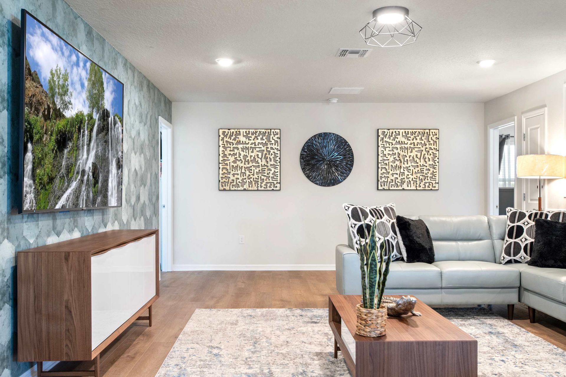 Modern lounge with sleek sectional, large smart TV, and eye-catching wall art.
