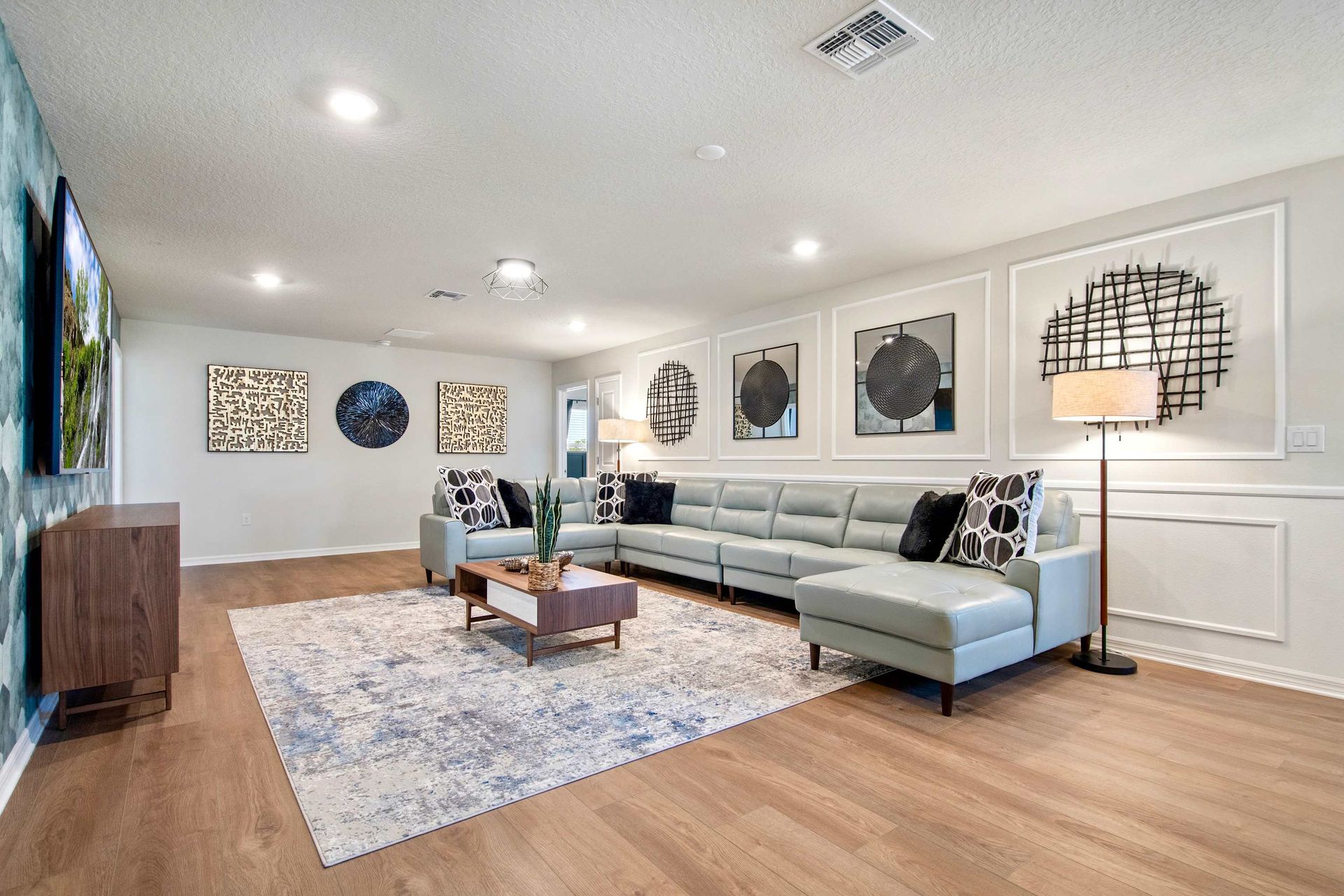 Spacious media room with modern sectional, designer accents, and immersive TV setup.
