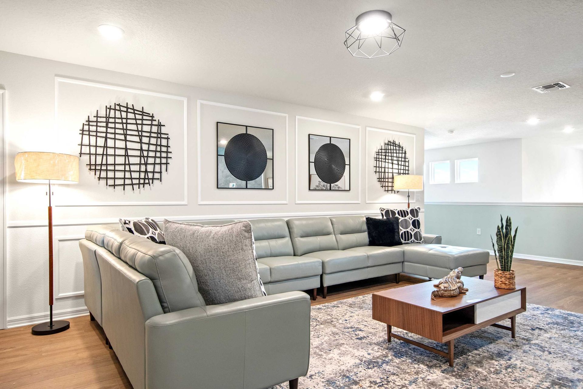 Chic upstairs lounge with sleek sectional, modern art, and cozy lighting.
