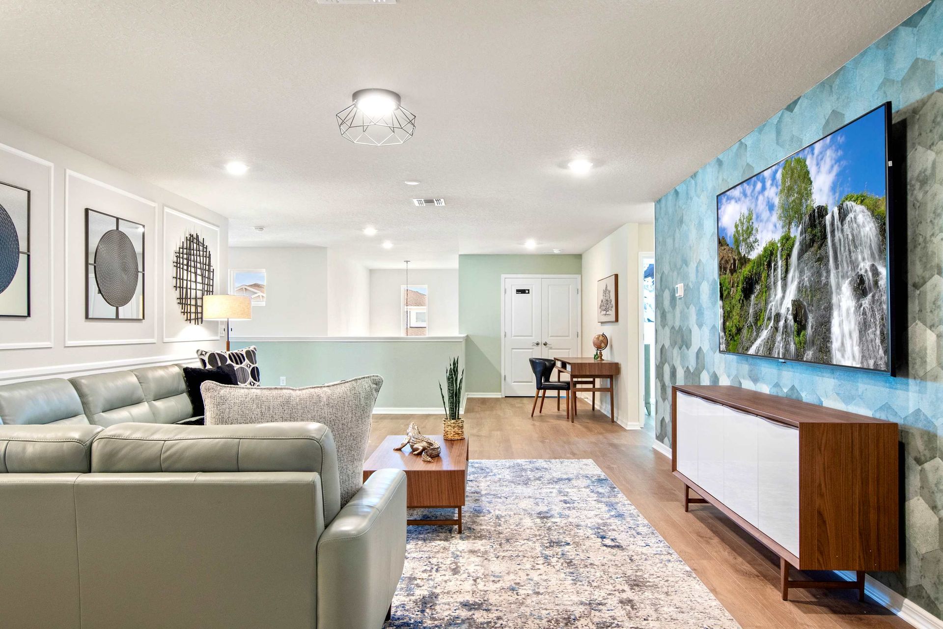 Bright upstairs loft with large TV, stylish sectional, workspace, and modern flair.
