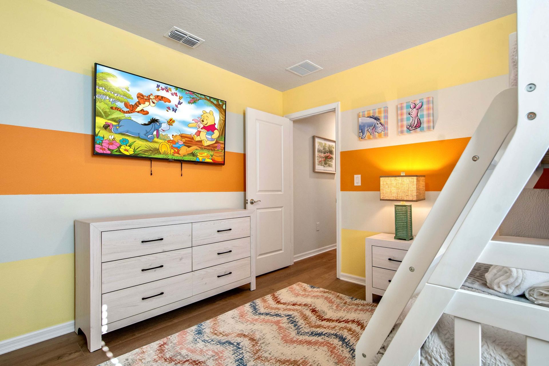 Fun-filled kids’ room with bold stripes, smart TV, and twin-over-full bunk bed.
