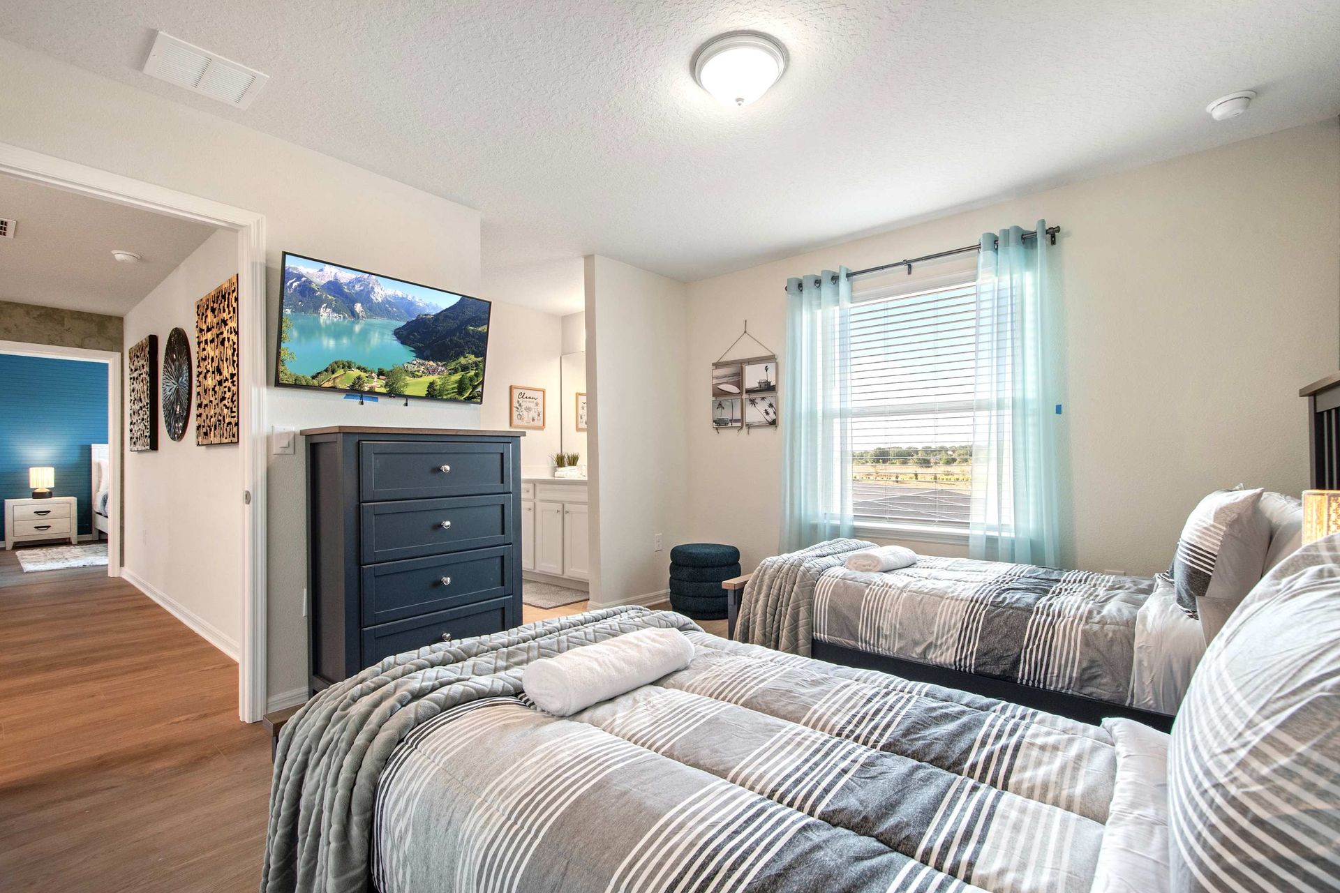 Comfortable twin bedroom with smart TV, natural light, and direct bathroom access.
