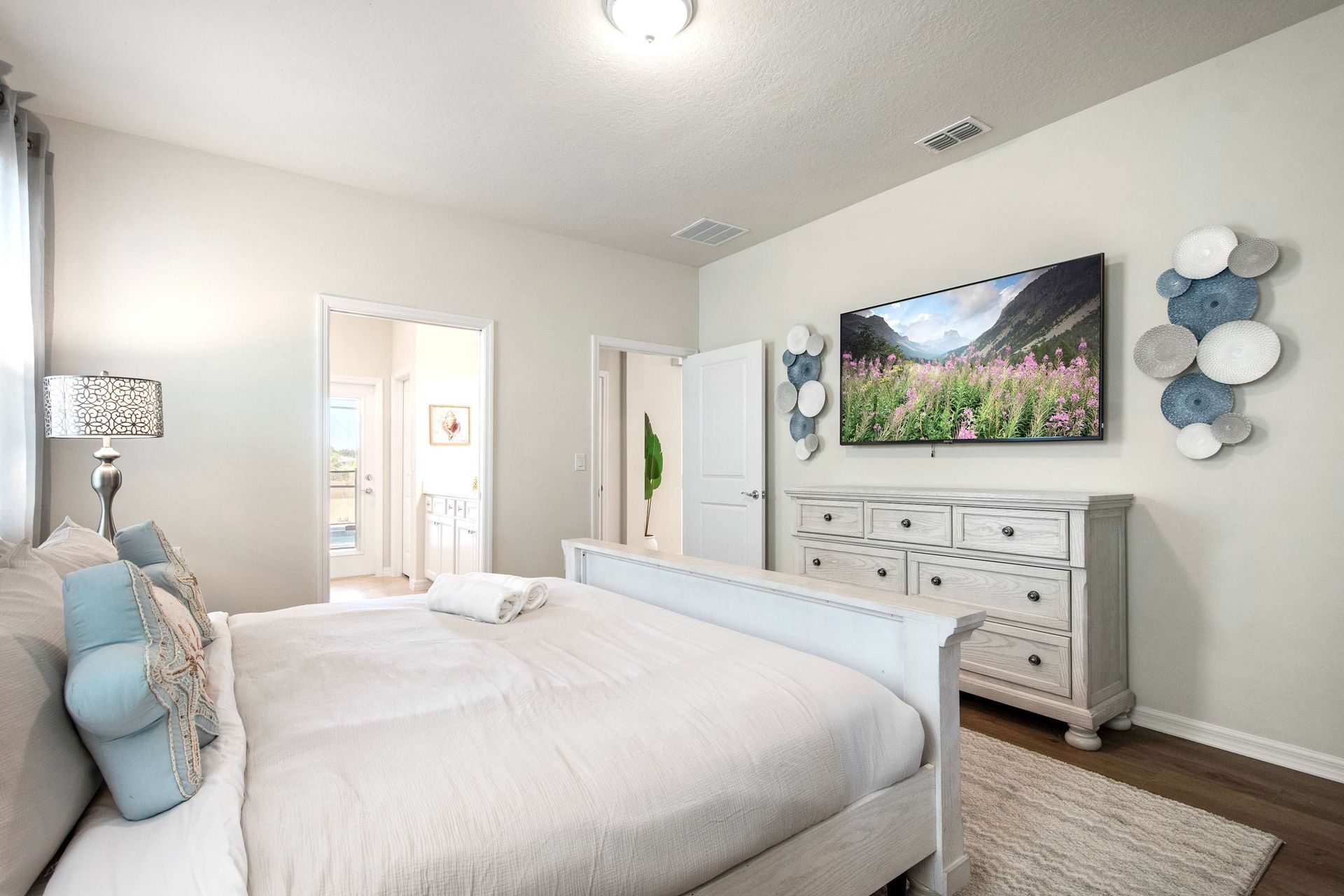 Elegant king suite with ensuite bath, smart TV, and soft, coastal-inspired decor.

