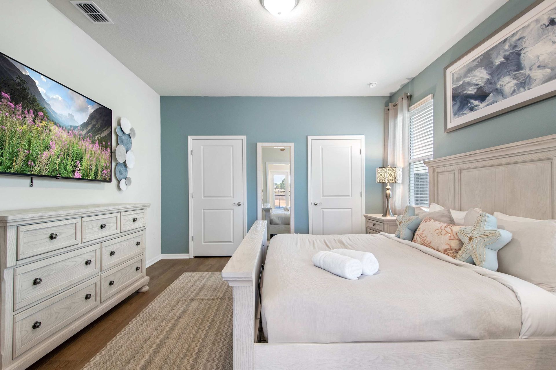 Spacious main bedroom with plush king bed, smart TV, and calming blue tones.
