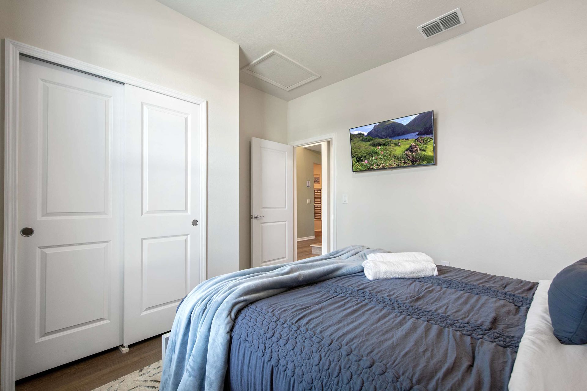 Comfortable queen bedroom with sleek design, smart TV, and private bathroom access.
