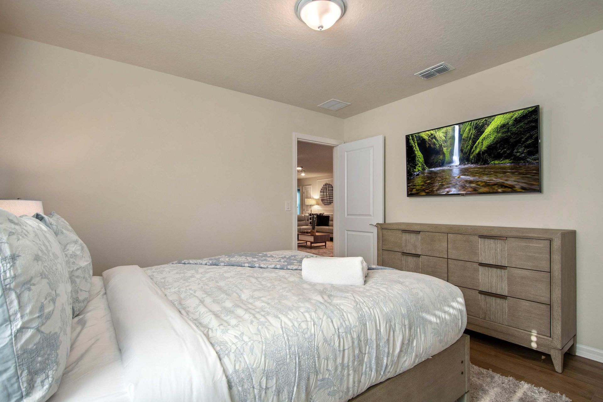 Cozy queen room with smart TV, soft bedding, and calming neutral decor.
