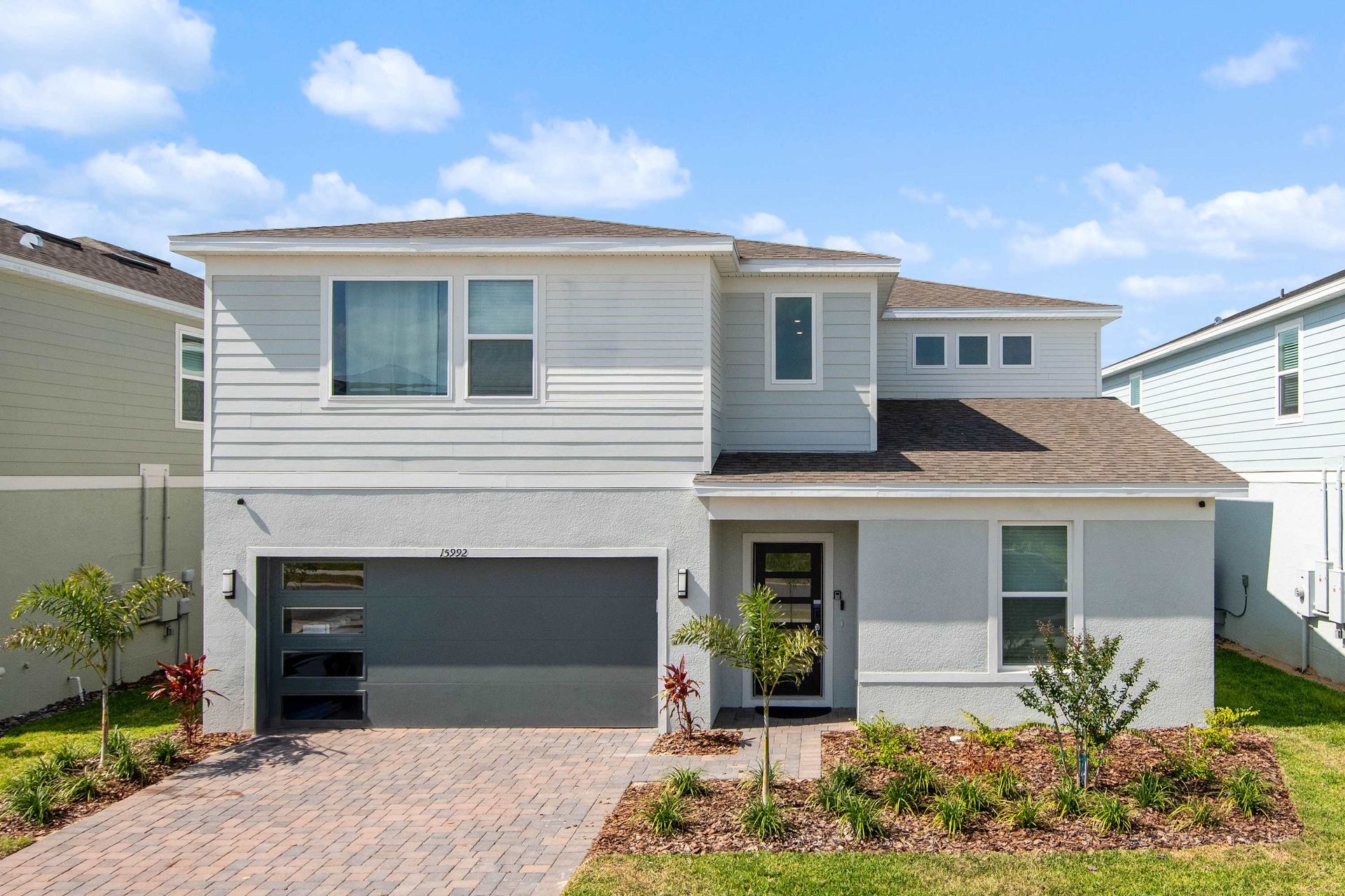 Modern two-story home with stylish exterior, lush landscaping, and spacious driveway.
