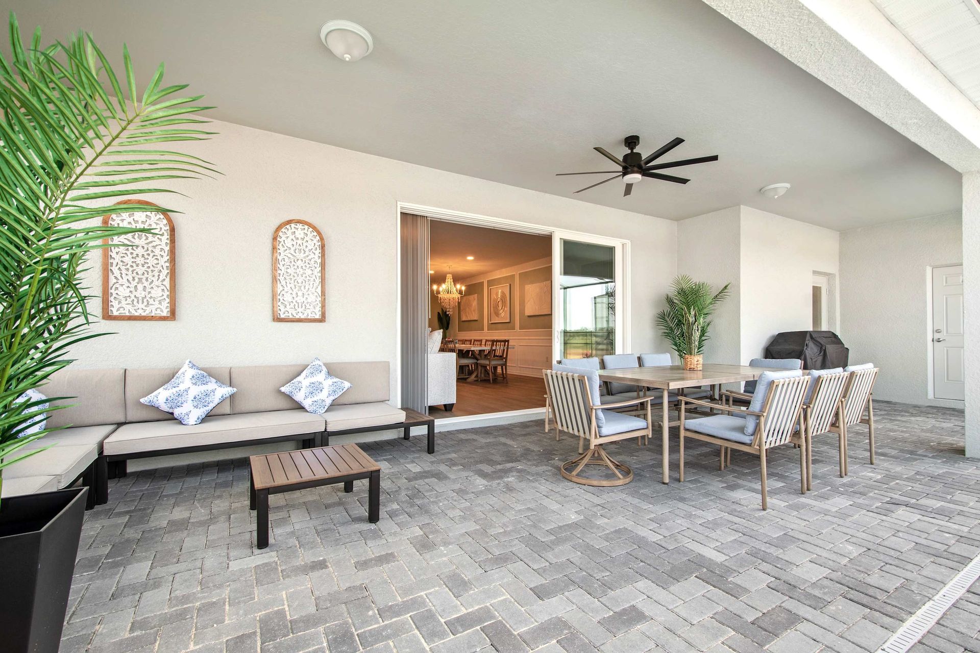Stylish covered patio with dining, lounge seating, ceiling fan, and BBQ grill.
