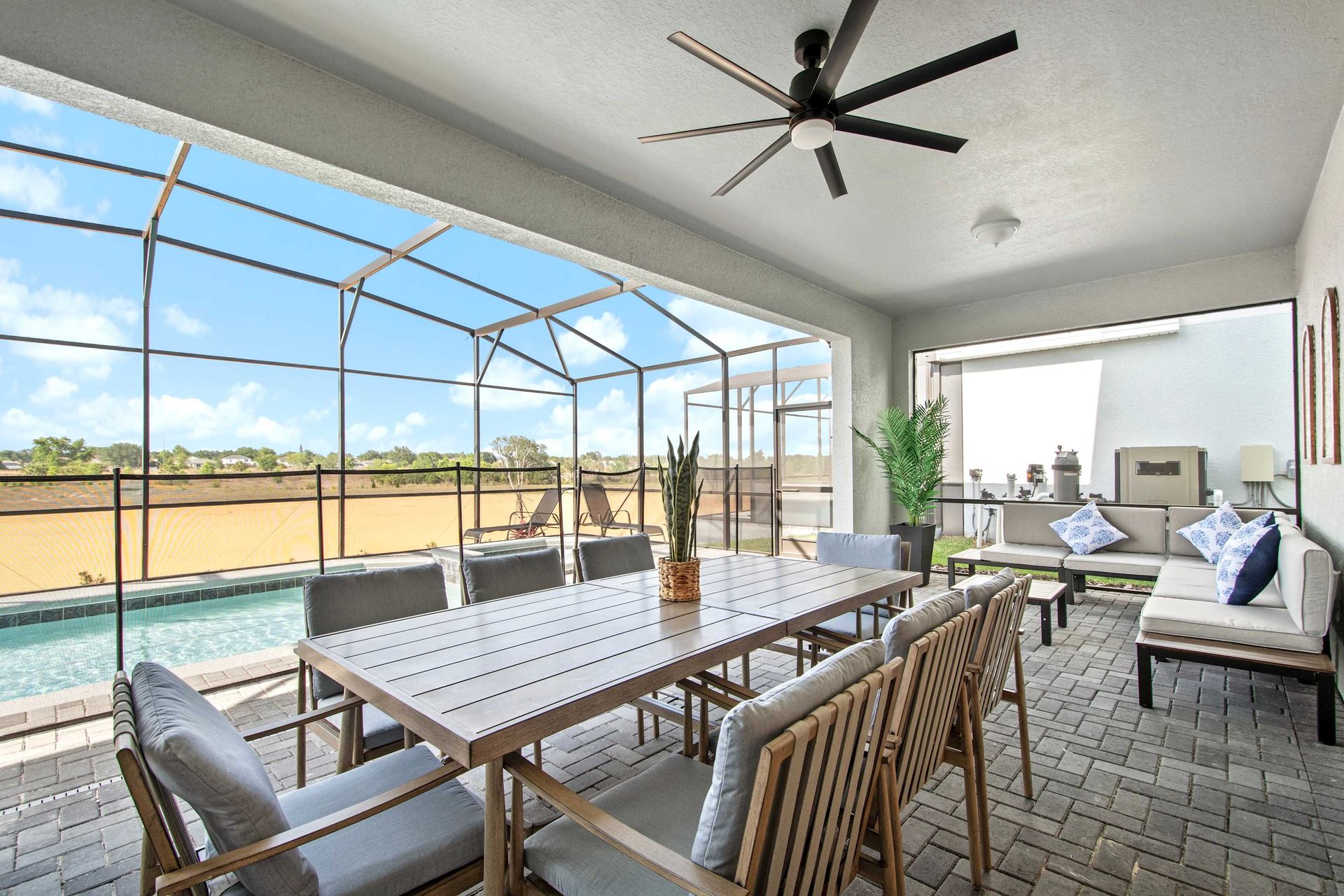Spacious lanai with screened pool, dining for eight, lounge area, and ceiling fan.
