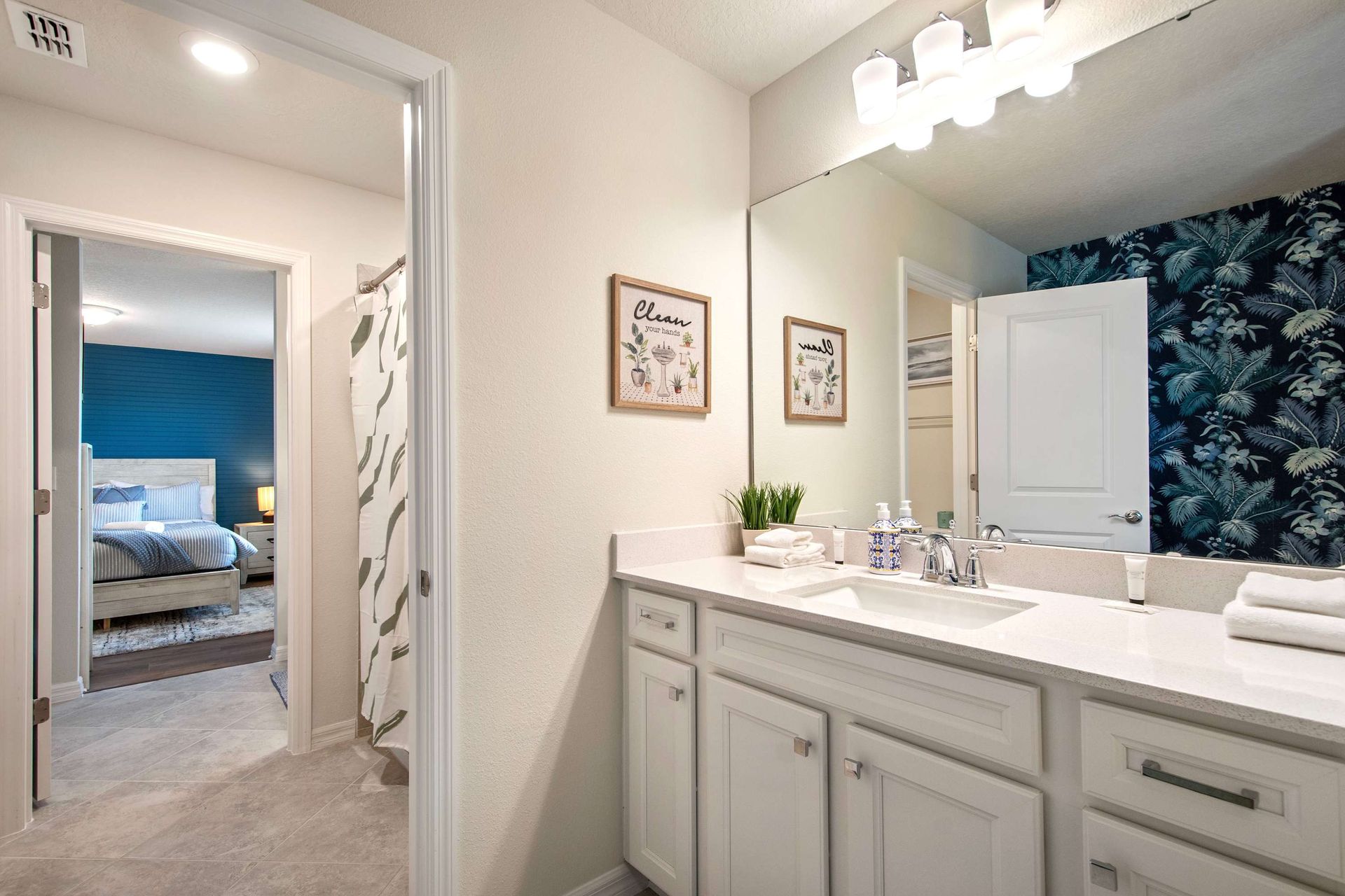 Bright shared bathroom with dual vanity, modern lighting, and vibrant accent wall.
