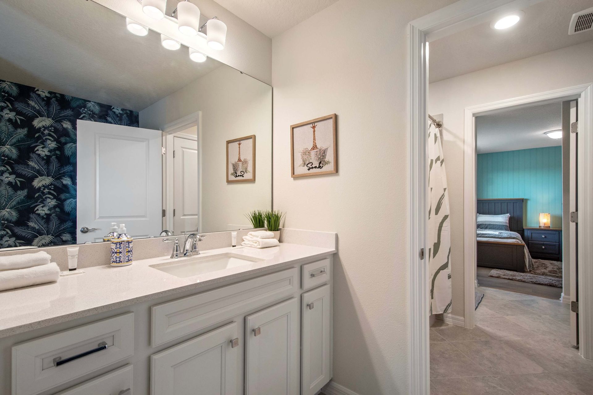 Bright shared bathroom with dual vanity, modern lighting, and vibrant accent wall.
