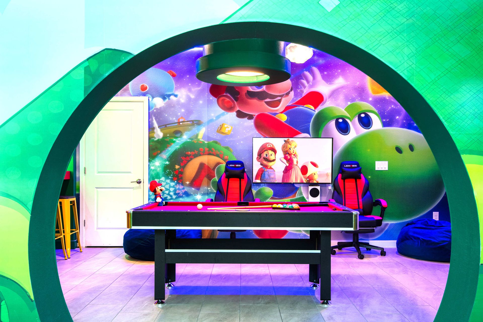 Super Mario gaming lounge with vibrant neon lights, wall art, and console setups!

