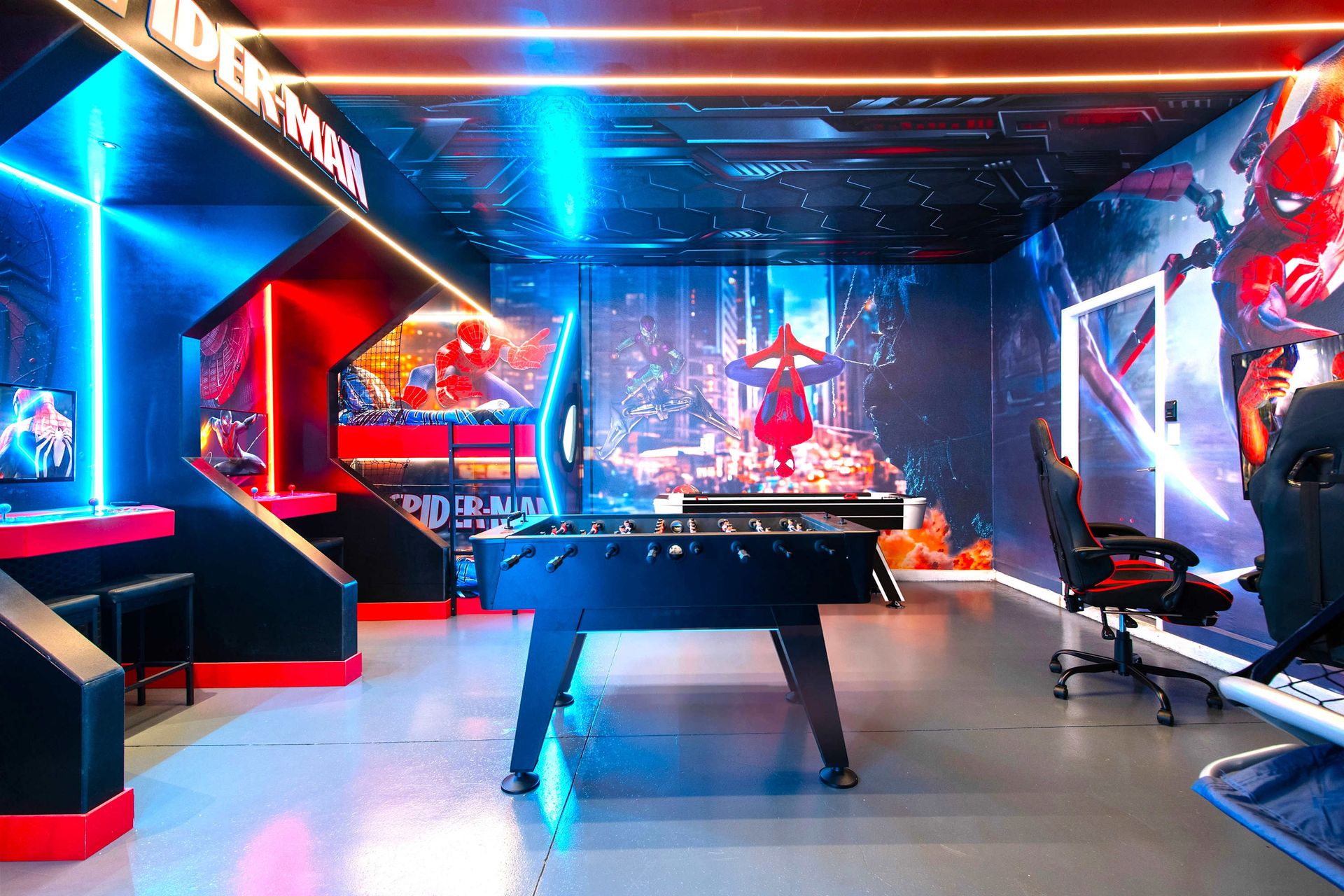 Ultimate Spider-Man game room with foosball, gaming chairs, and bold decor.
