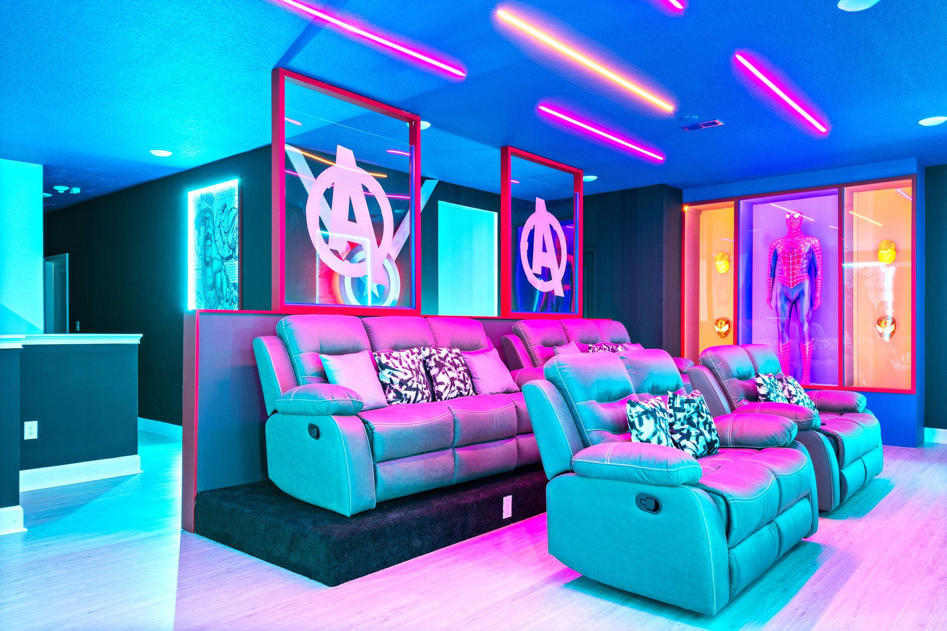 Vibrant superhero home theater with tiered recliners and glowing neon ambiance
