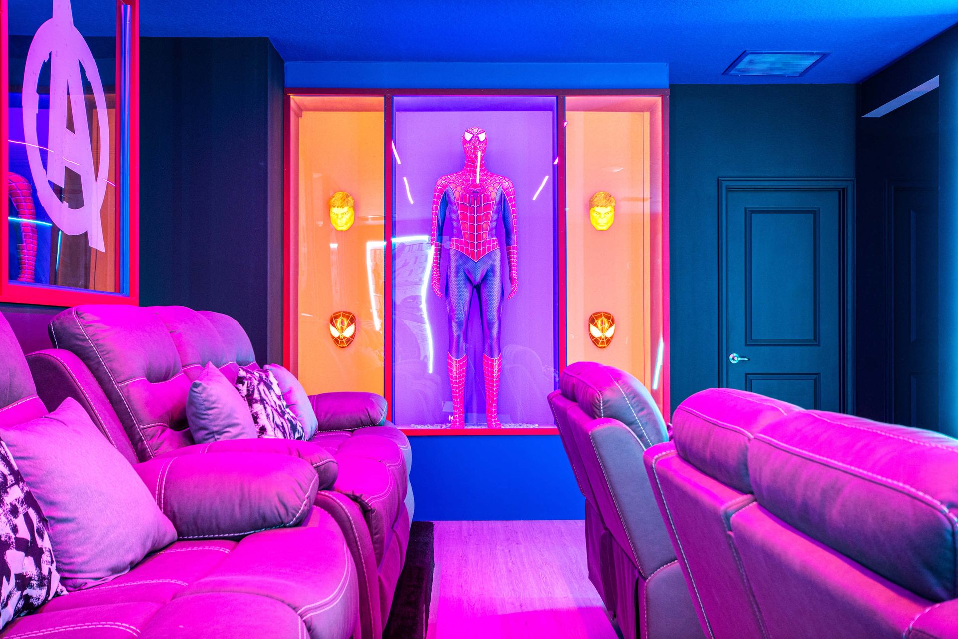 Vibrant superhero home theater with tiered recliners and glowing neon ambiance
